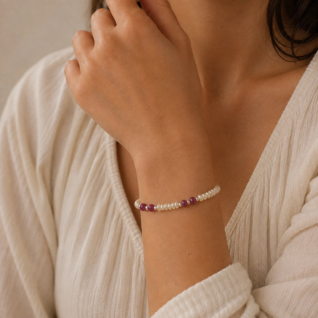 Pearl_bracelet_with_pearl_and_ruby_stones_in_gold_plated_silver_at_front_angle_view_on_soft_fabric_background