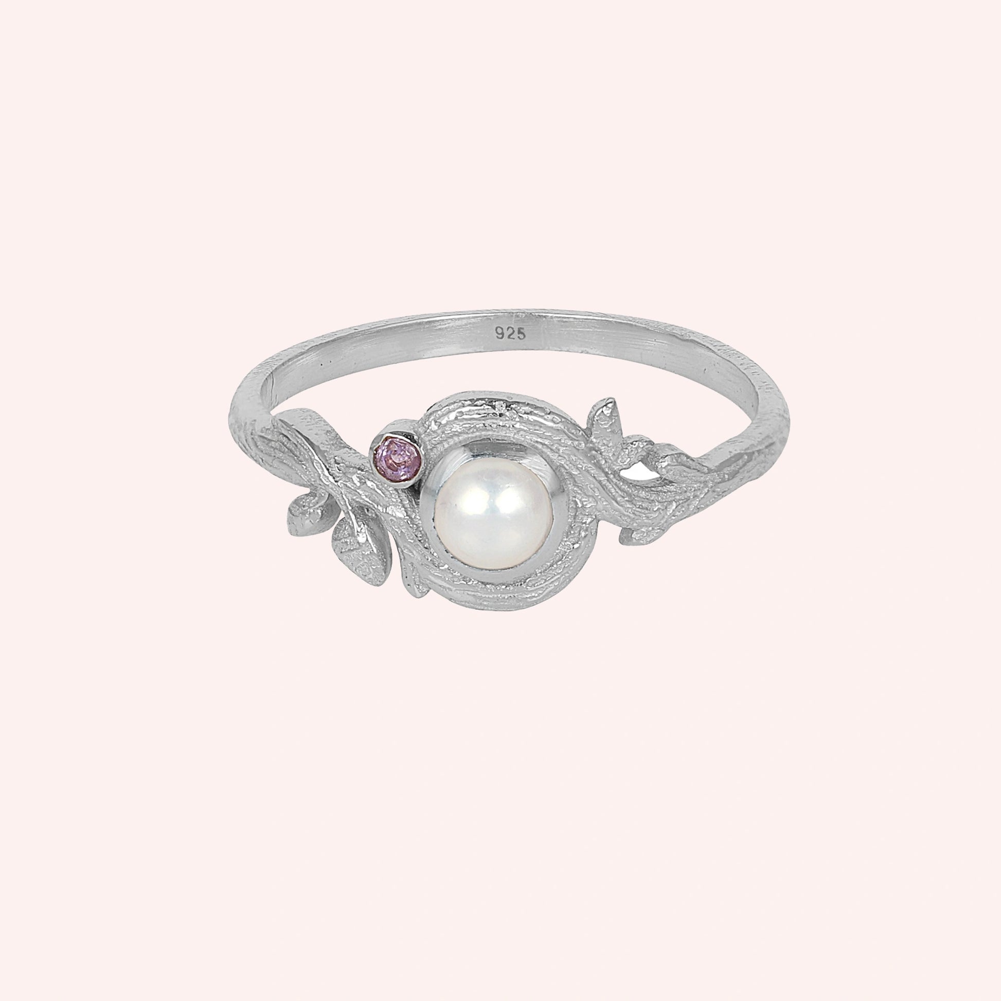 Pearl_ring_in_sterling_silver_with_pearl_and_amethyst_stones_in_a_floral_design_at_front_angle_view_on_solid_pink_background