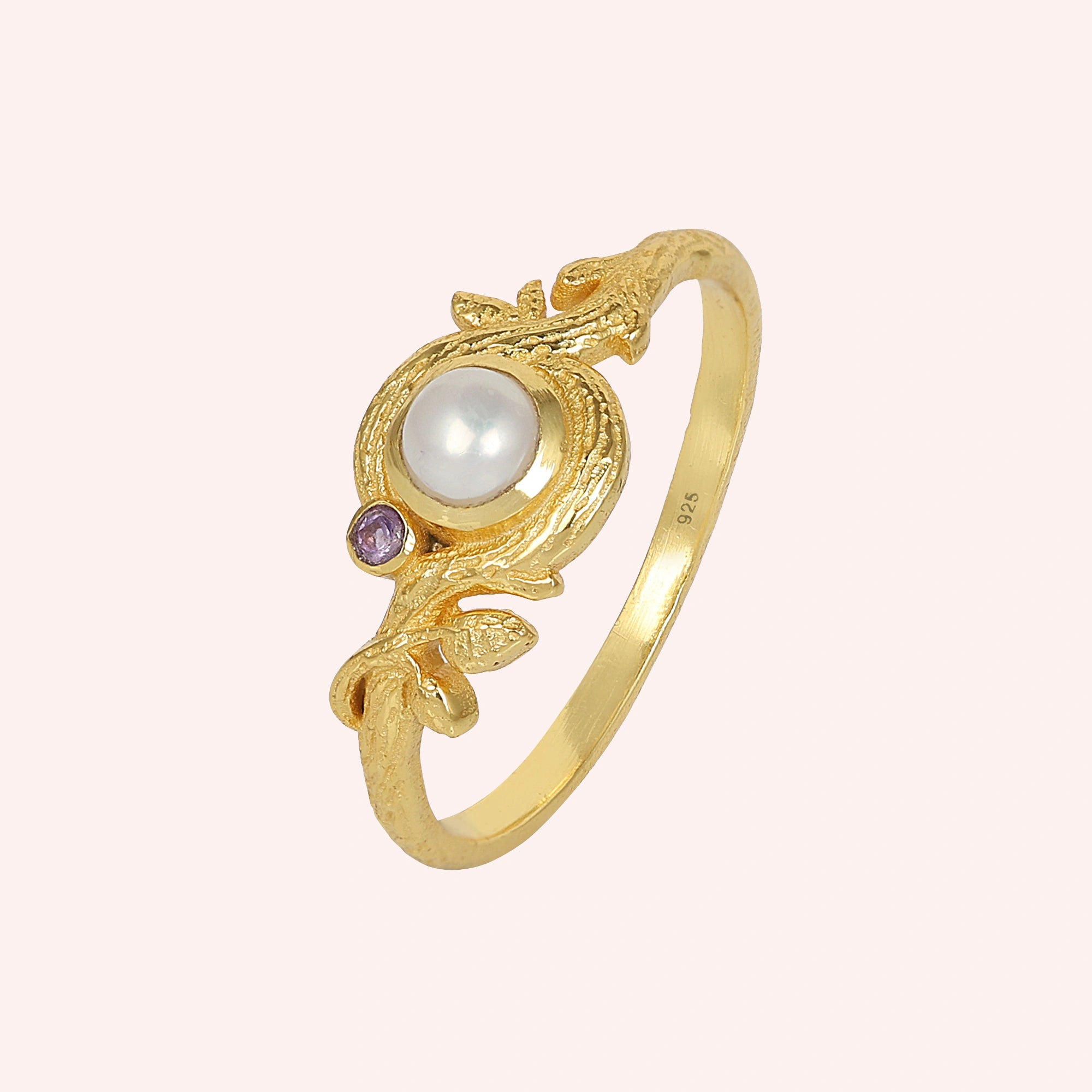 Pearl_ring_in_gold_plated_silver_with_pearl_and_amethyst_stones_in_a_floral_design_at_slight_angle_view_on_solid_pink_background