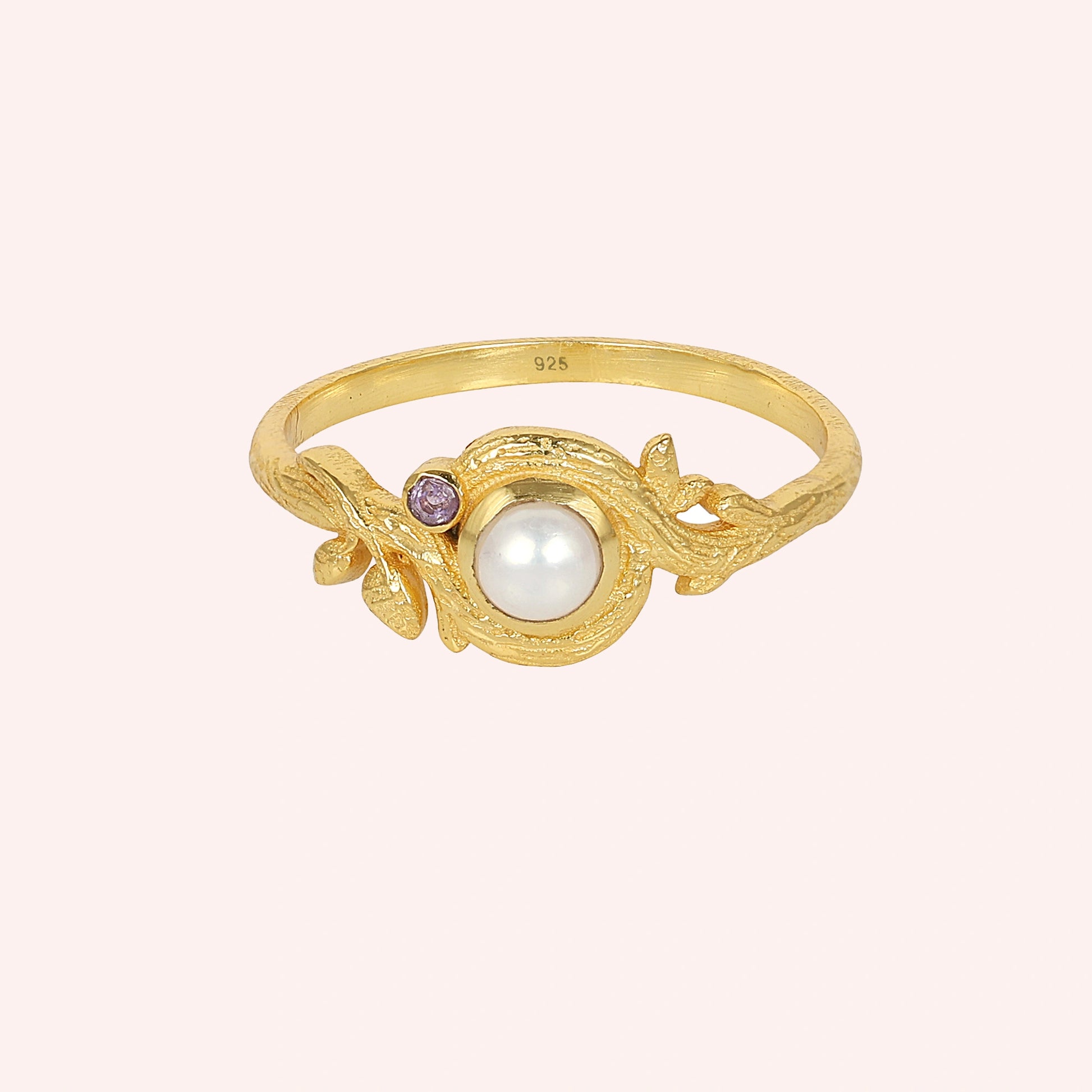 Pearl_ring_in_gold_plated_silver_with_pearl_and_amethyst_stones_in_a_floral_design_at_front_angle_view_on_solid_pink_background