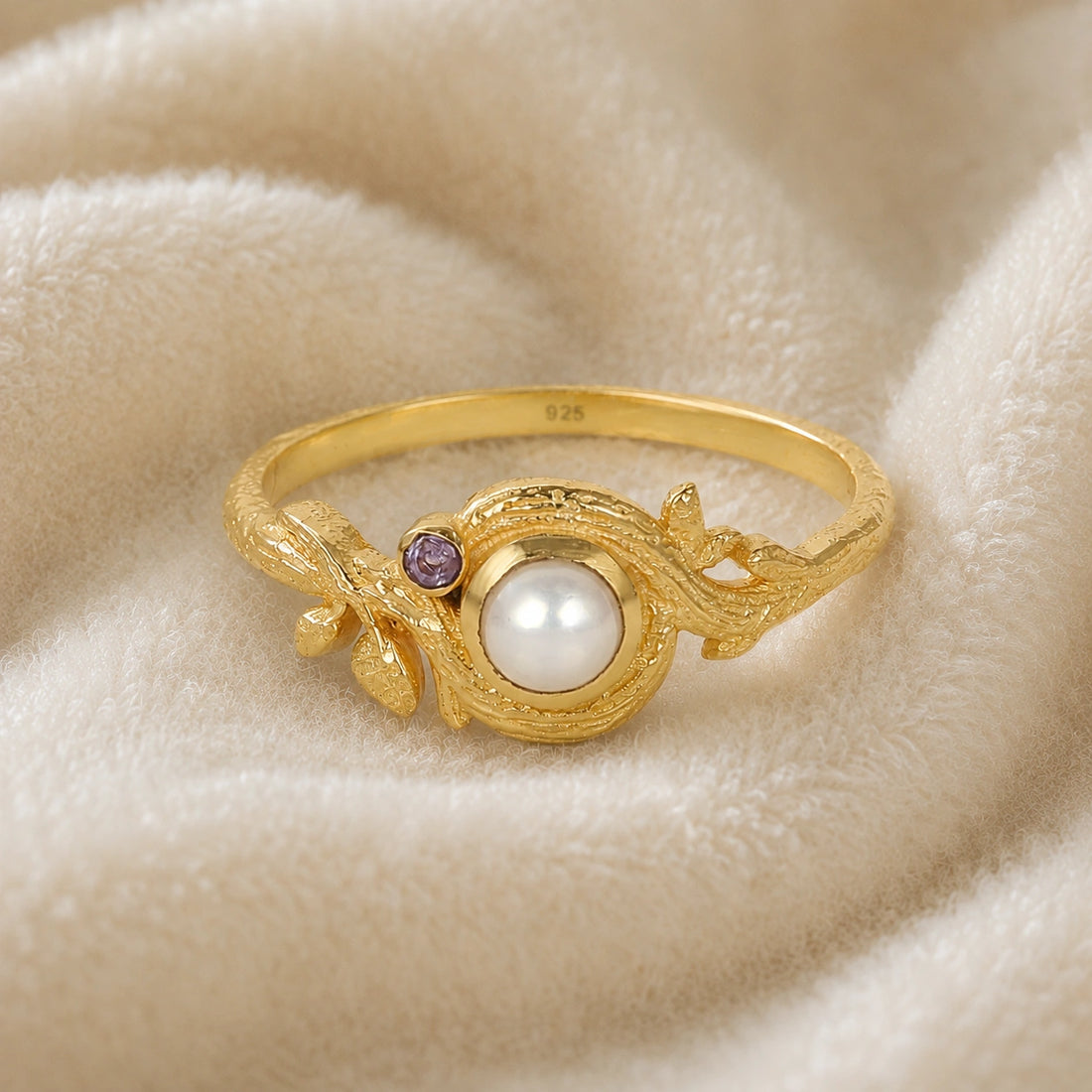 Pearl_ring_in_gold_plated_silver_with_pearl_and_amethyst_stones_in_a_floral_design_at_front_angle_view_on_soft_fabric_background