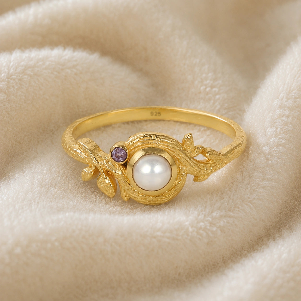 Pearl_ring_in_gold_plated_silver_with_pearl_and_amethyst_stones_in_a_floral_design_at_front_angle_view_on_soft_fabric_background