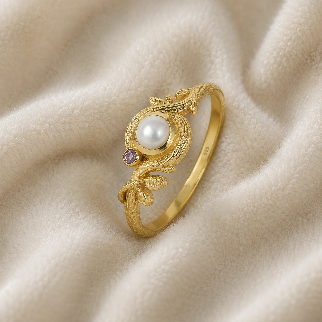 Pearl_ring_in_gold_plated_silver_with_pearl_and_amethyst_stones_in_a_floral_design_at_slight_angle_view_on_soft_fabric_background