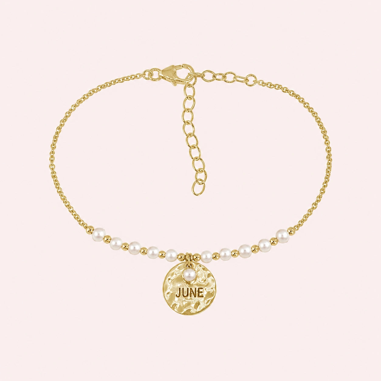 Birthstone_bracelet_in_gold_plated_silver_with_June_charm_and_pearl_beads_on_fine_chain_on_solid_pink_background
