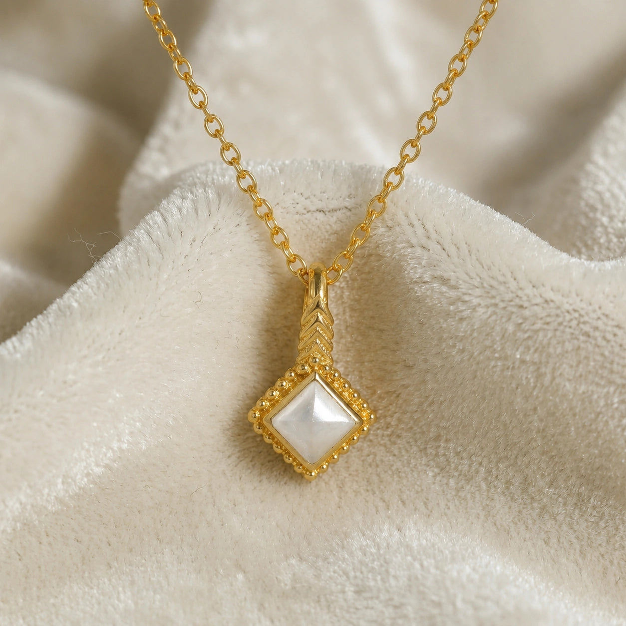 Birthstone_necklace_in_gold_plated_silver_with_square_cut_pearl_pendant_in_front_angle_view_on_soft_white_fabric_background