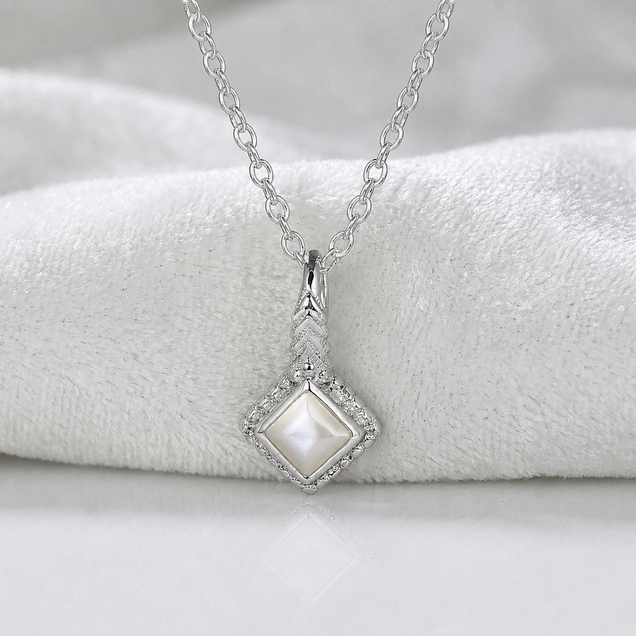 Birthstone_necklace_in_sterling_silver_with_square_cut_pearl_pendant_in_front_angle_view_on_soft_white_fabric_background