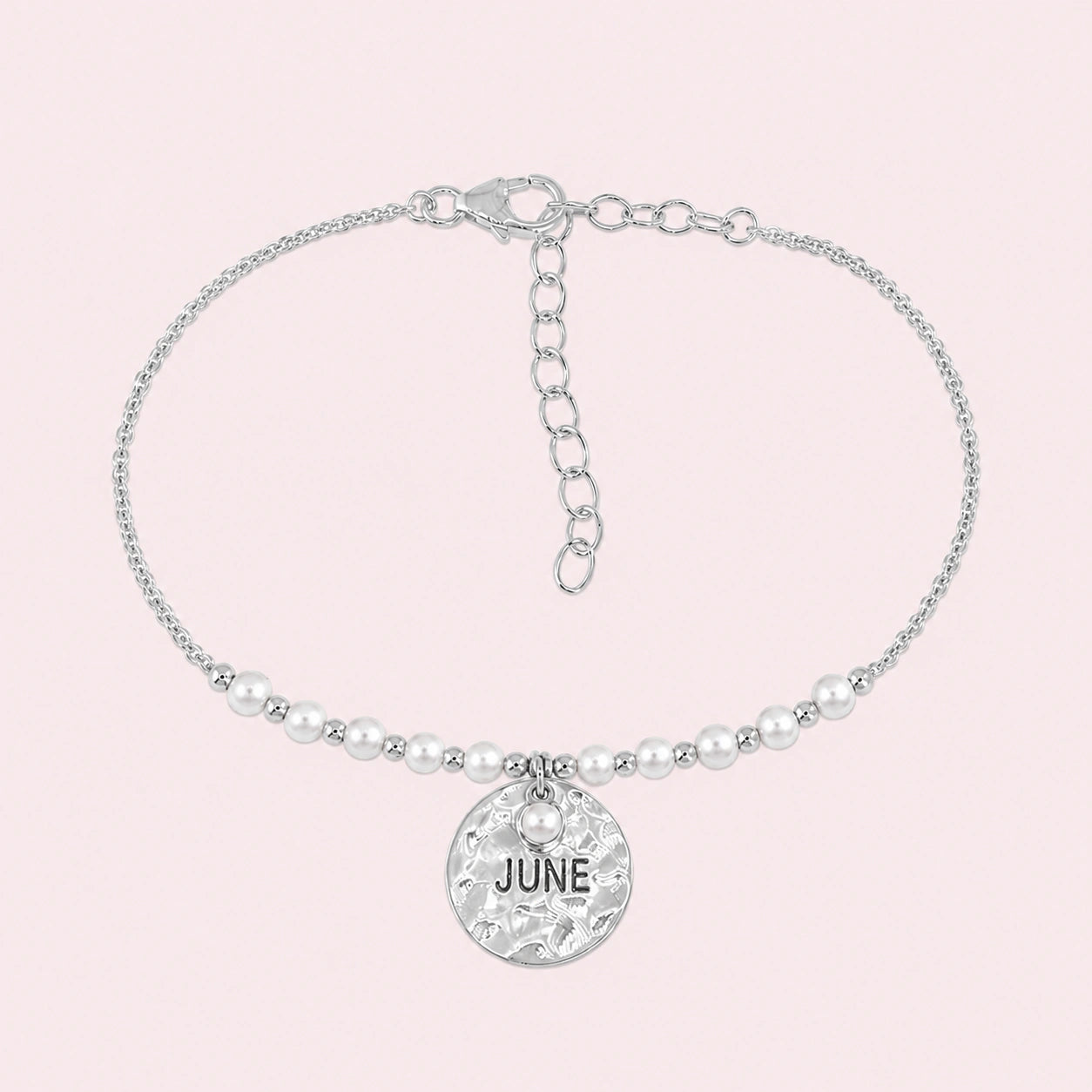 Birthstone_bracelet_in_sterling_silver_with_June_charm_and_pearl_beads_on_fine_chain_on_solid_pink_background