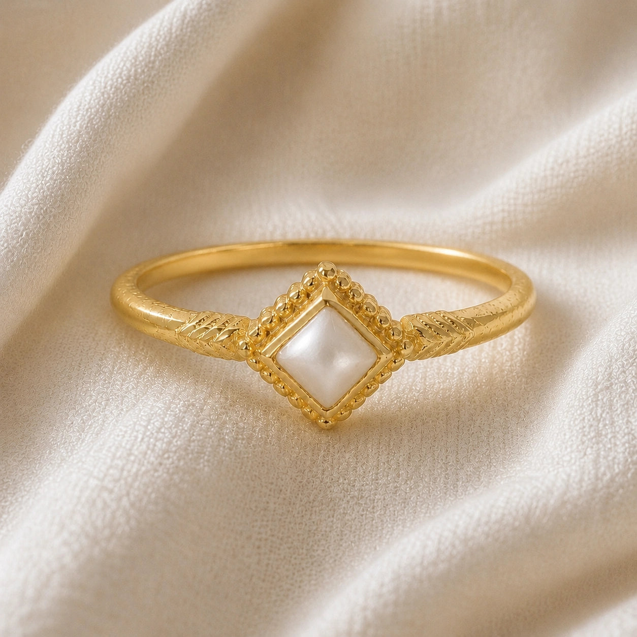 Princess_cut_ring_gold_plated_silver_with_square_pearl_and_detailed_band_front_angle_view_on_soft_fabric_background
