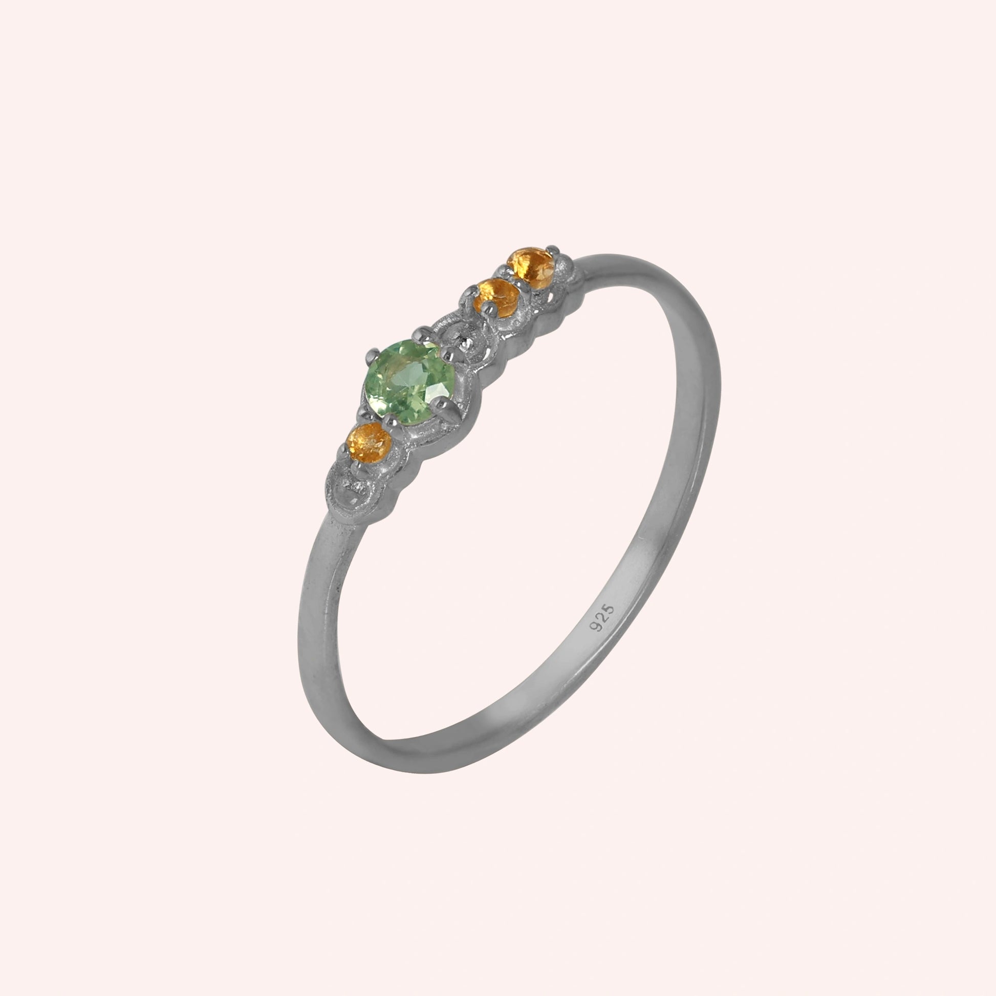 Peridot-ring-with-peridot-and-citrine-gemstones-sterling-silver-angled-view-on-soft-pink-background