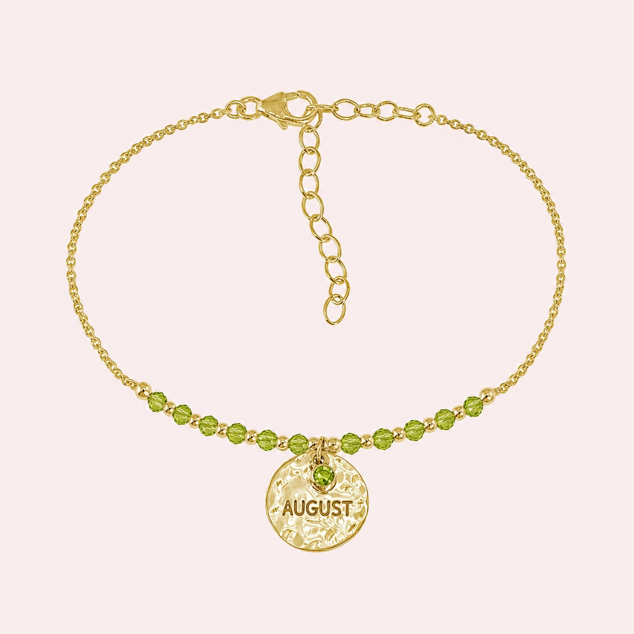 Birthstone_bracelet_in_gold_plated_silver_with_August_charm_and_peridot_beads_on_fine_chain_on_solid_pink_background