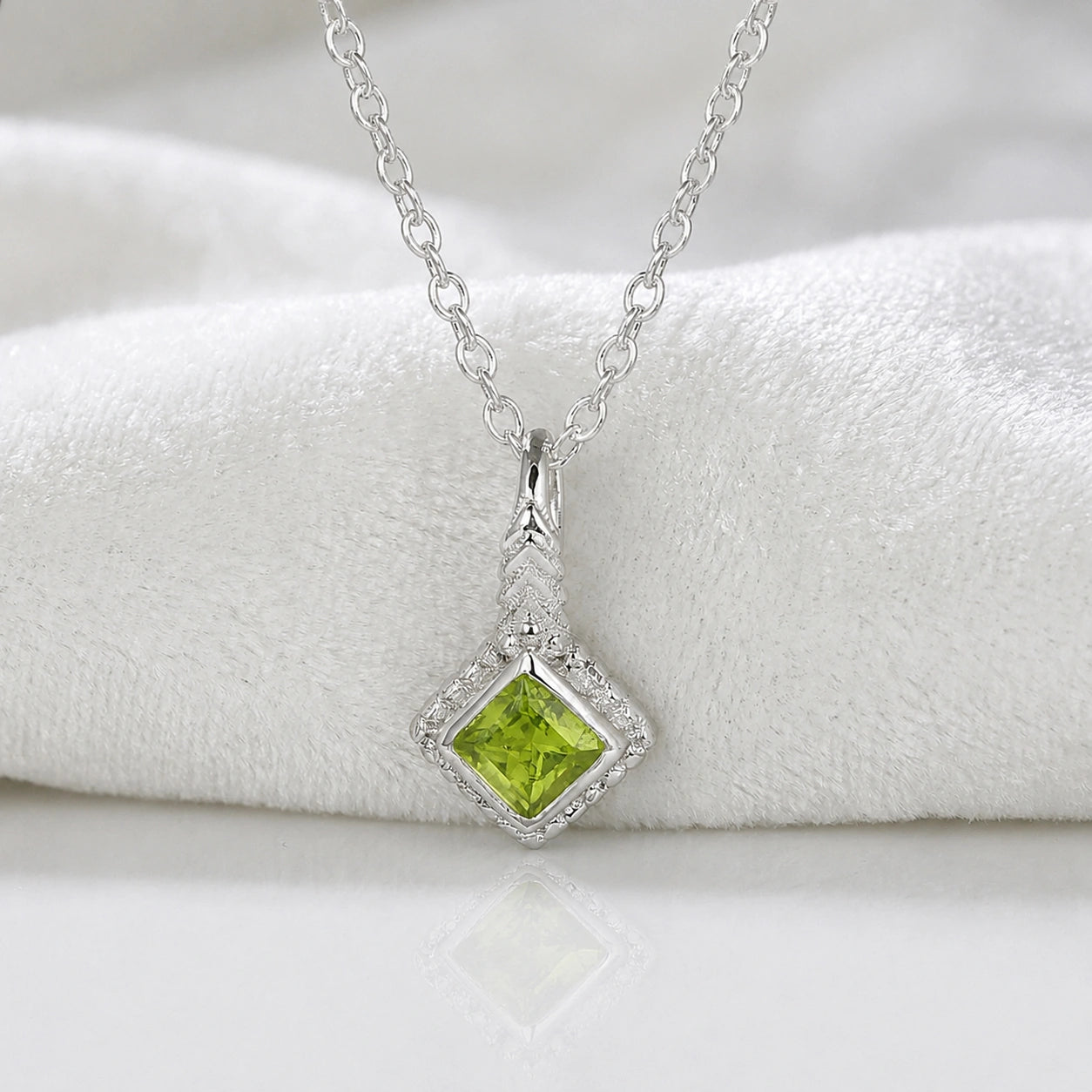 Birthstone_necklace_in_sterling_silver_with_square_cut_peridot_pendant_in_front_angle_view_on_soft_white_fabric_background