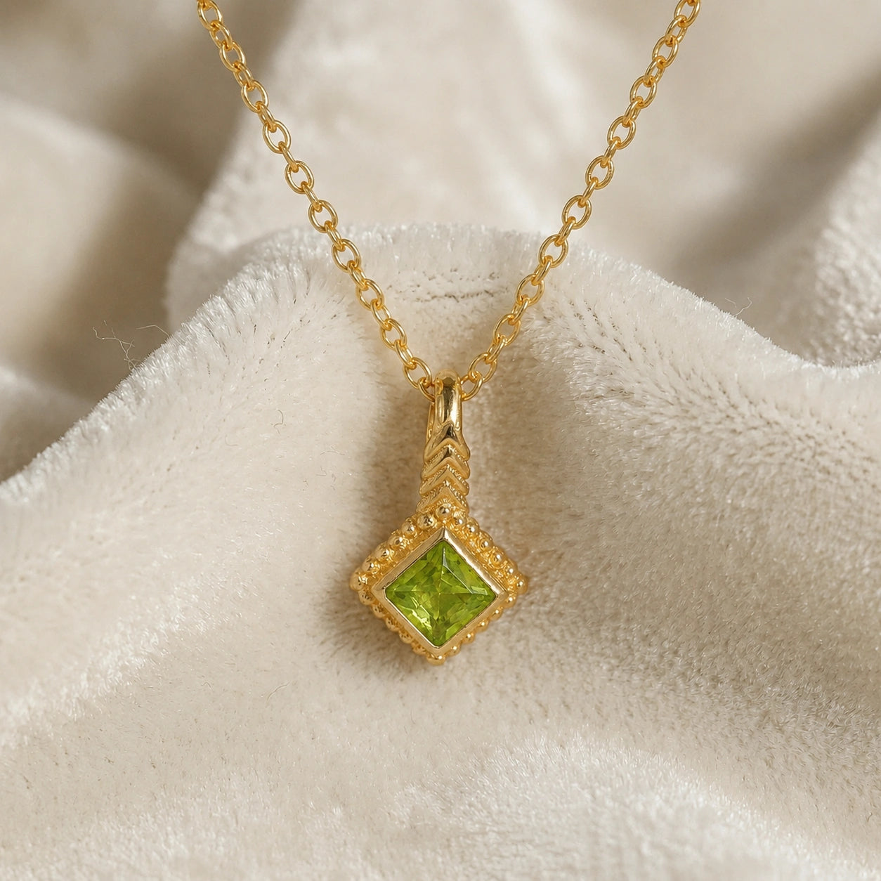 Birthstone_necklace_in_gold_plated_silver_with_square_cut_peridot_pendant_in_front_angle_view_on_soft_white_fabric_background