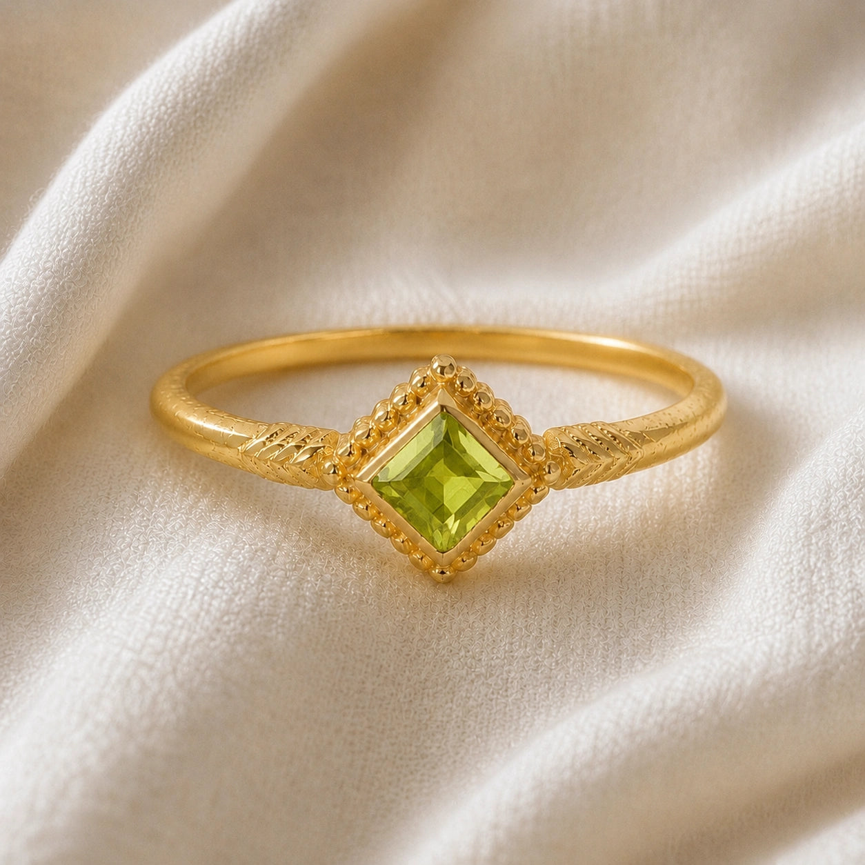 Princess_cut_ring_gold_plated_silver_with_square_peridot_and_detailed_band_front_angle_view_on_soft_fabric_background