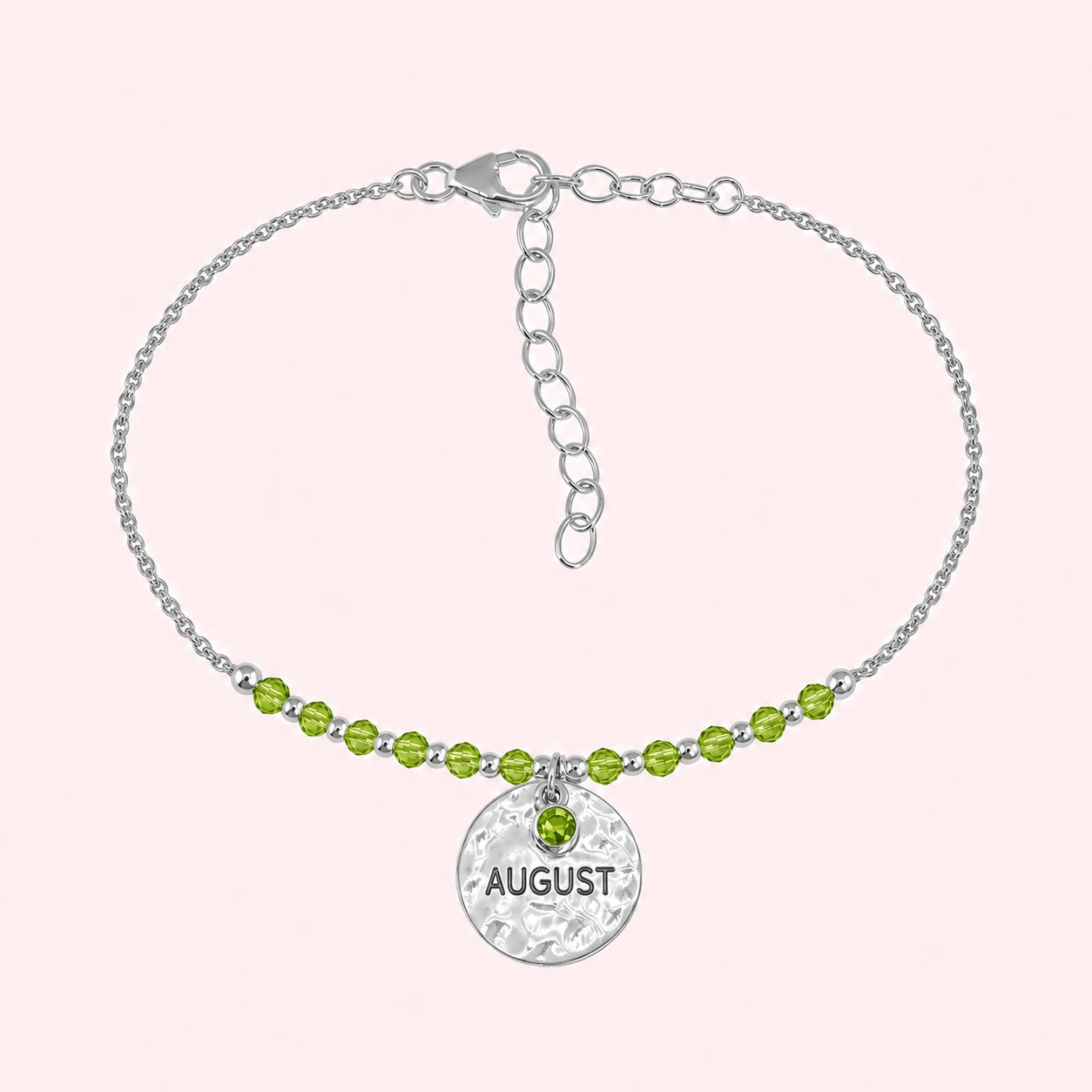 Birthstone_bracelet_in_sterling_silver_with_August_charm_and_peridot_beads_on_fine_chain_on_solid_pink_background