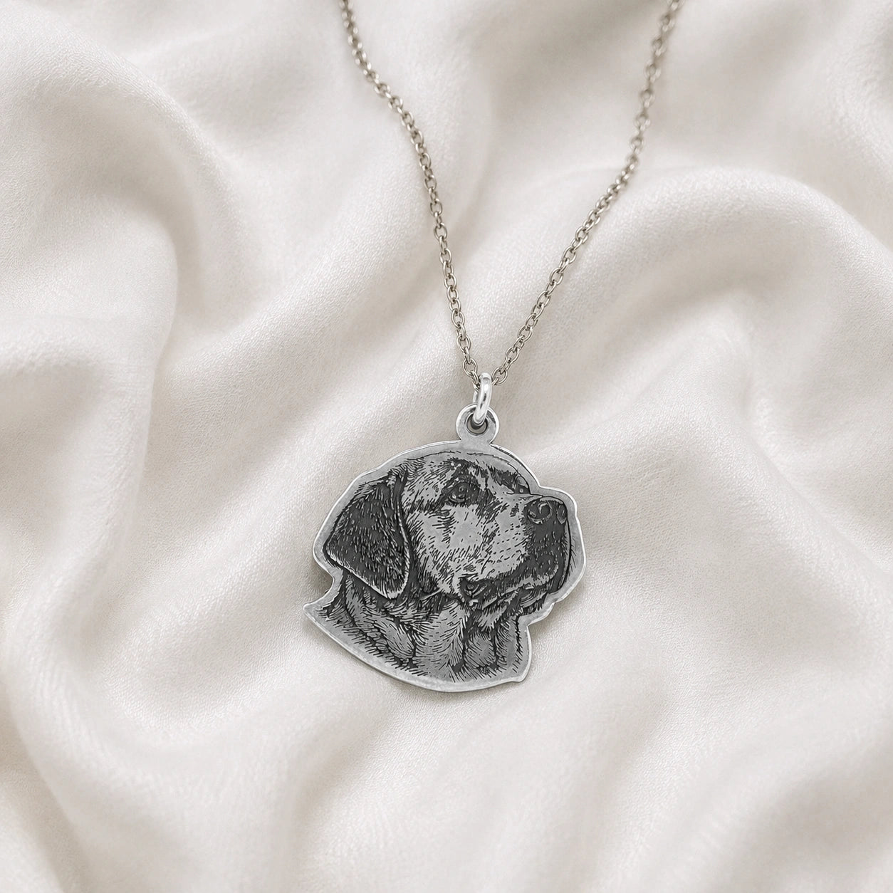 Pet_necklace_with_customized_engraved_dog_in_sterling_silver_at_slight_angle_on_a_soft_fabric_background