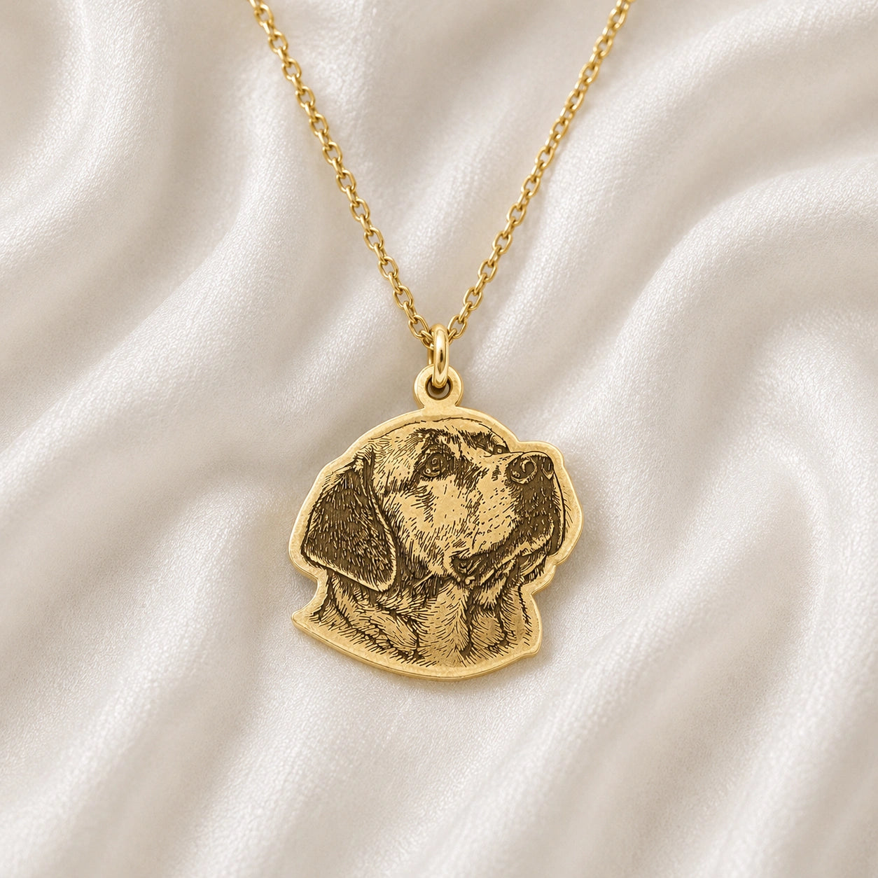 Pet_necklace_with_customized_engraved_dog_in_gold_plated_silver_at_slight_angle_on_a_soft_fabric_background