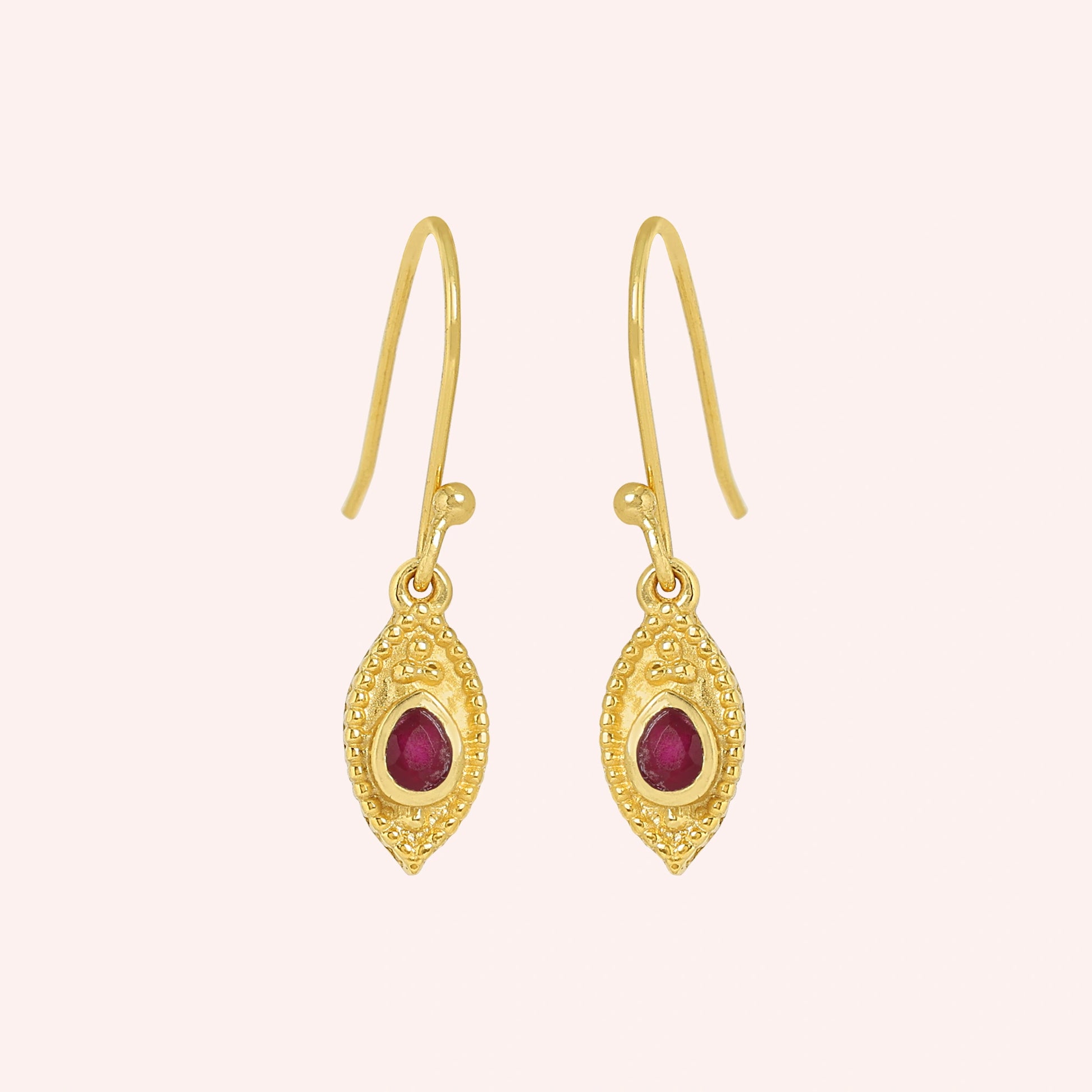 Pink_earrings_in_gold_plated_silver_with_pear_ruby_stones_at_front_angle_view_on_solid_pink_background