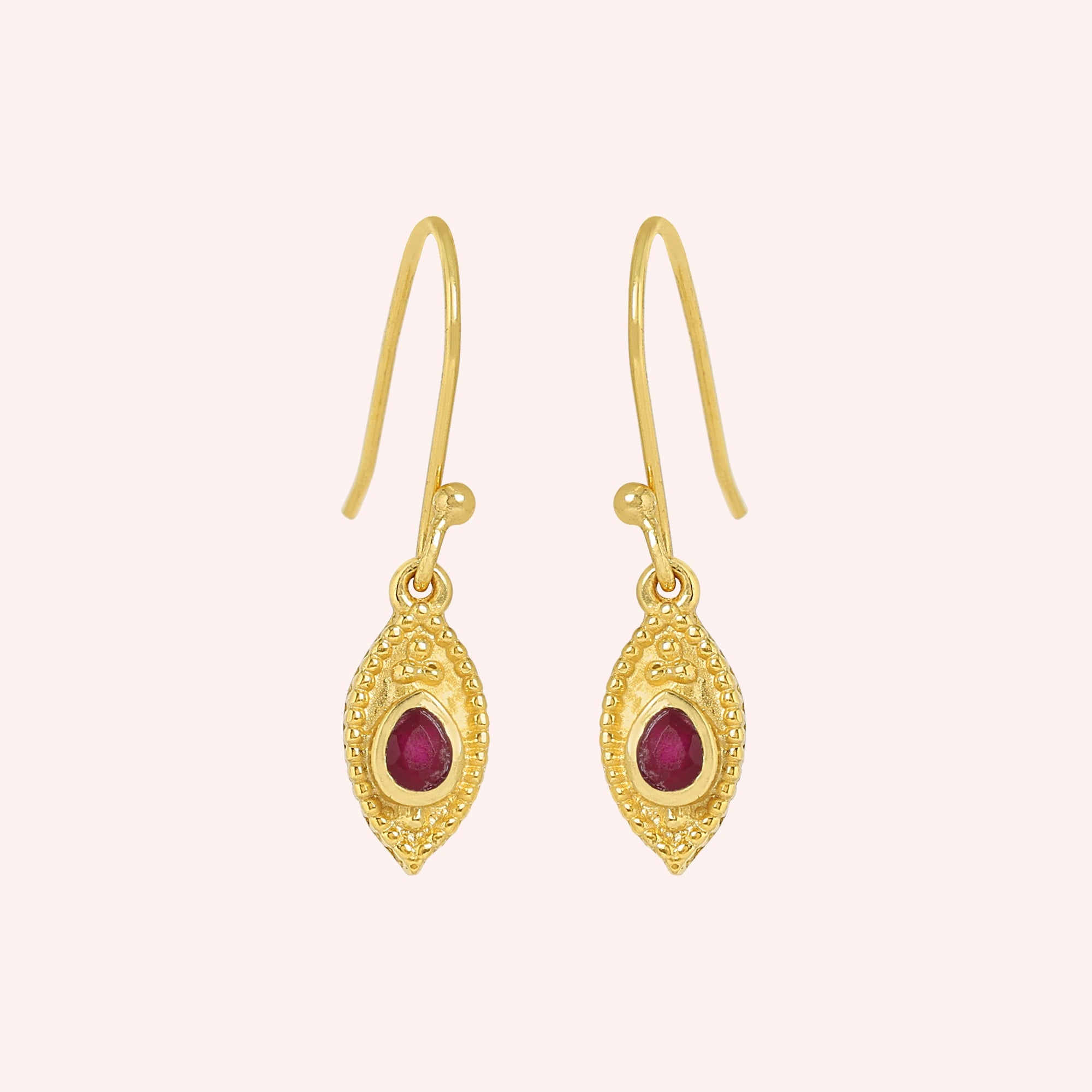 Pink_earrings_in_gold_plated_silver_with_pear_ruby_stones_at_front_angle_view_on_solid_pink_background