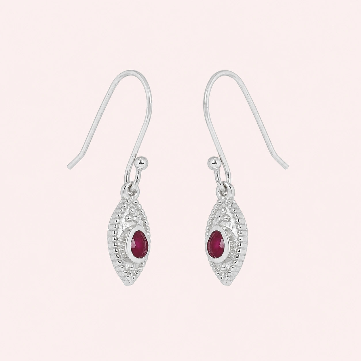 Pink_earrings_in_sterling_silver_with_pear_ruby_stones_at_slight_angle_view_on_solid_pink_background