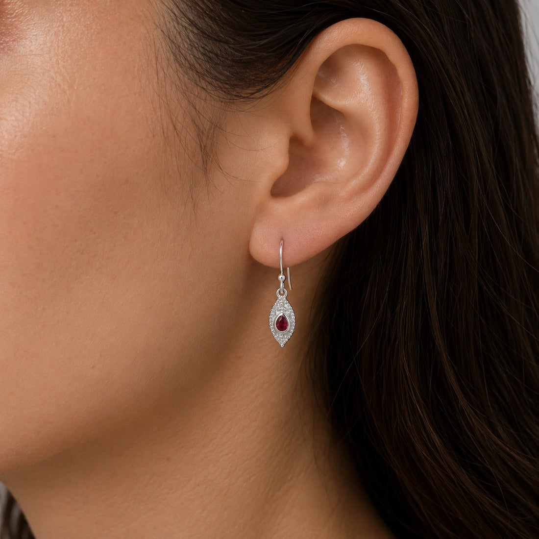 Pink_earrings_in_gold_plated_silver_with_pear_ruby_stones_at_front_angle_view_on_soft_fabric_background