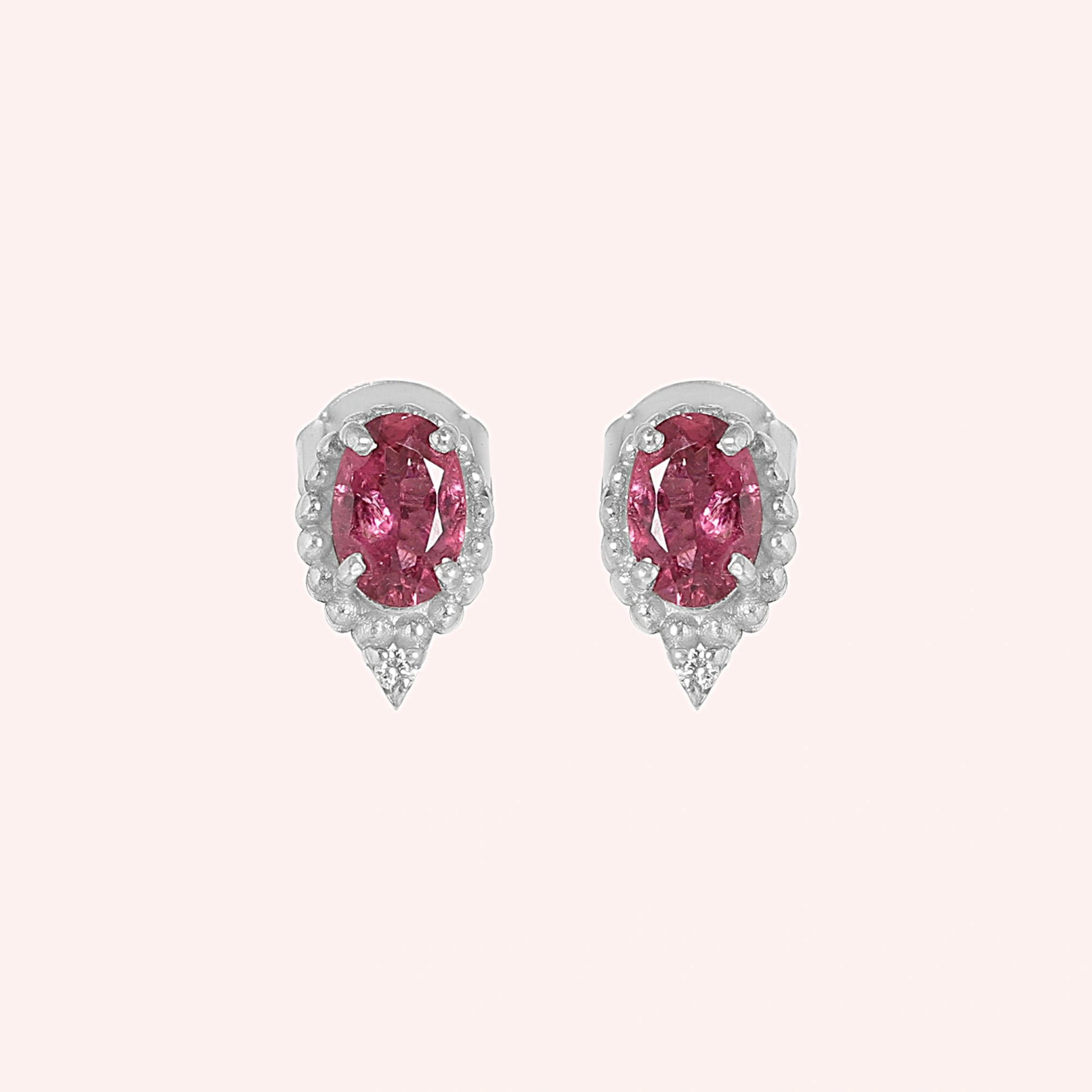 Pink_tourmaline_earrings_in_sterling_silver_with_oval_stone_and_a_white_topaz_shown_front_angle_view_on_solid_pink_background