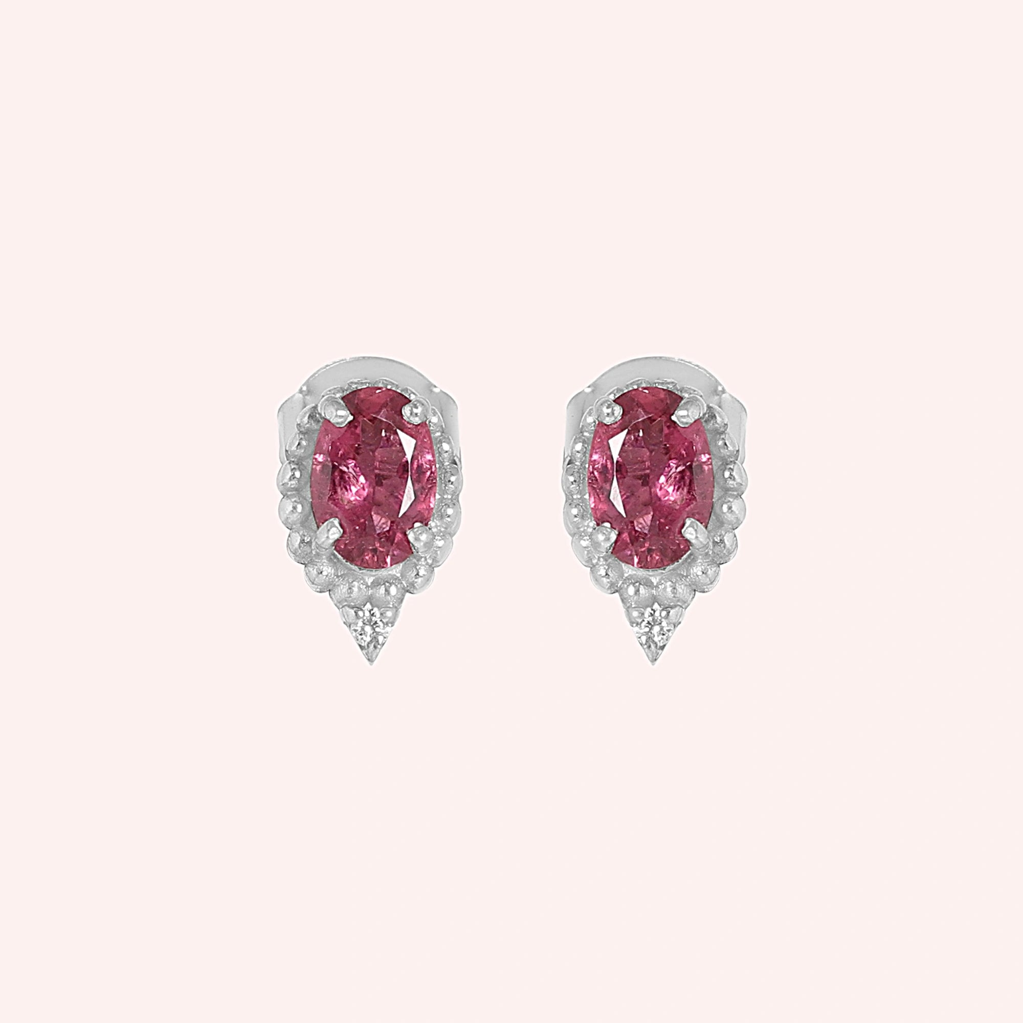 Pink_tourmaline_earrings_in_sterling_silver_with_oval_stone_and_a_white_topaz_shown_front_angle_view_on_solid_pink_background