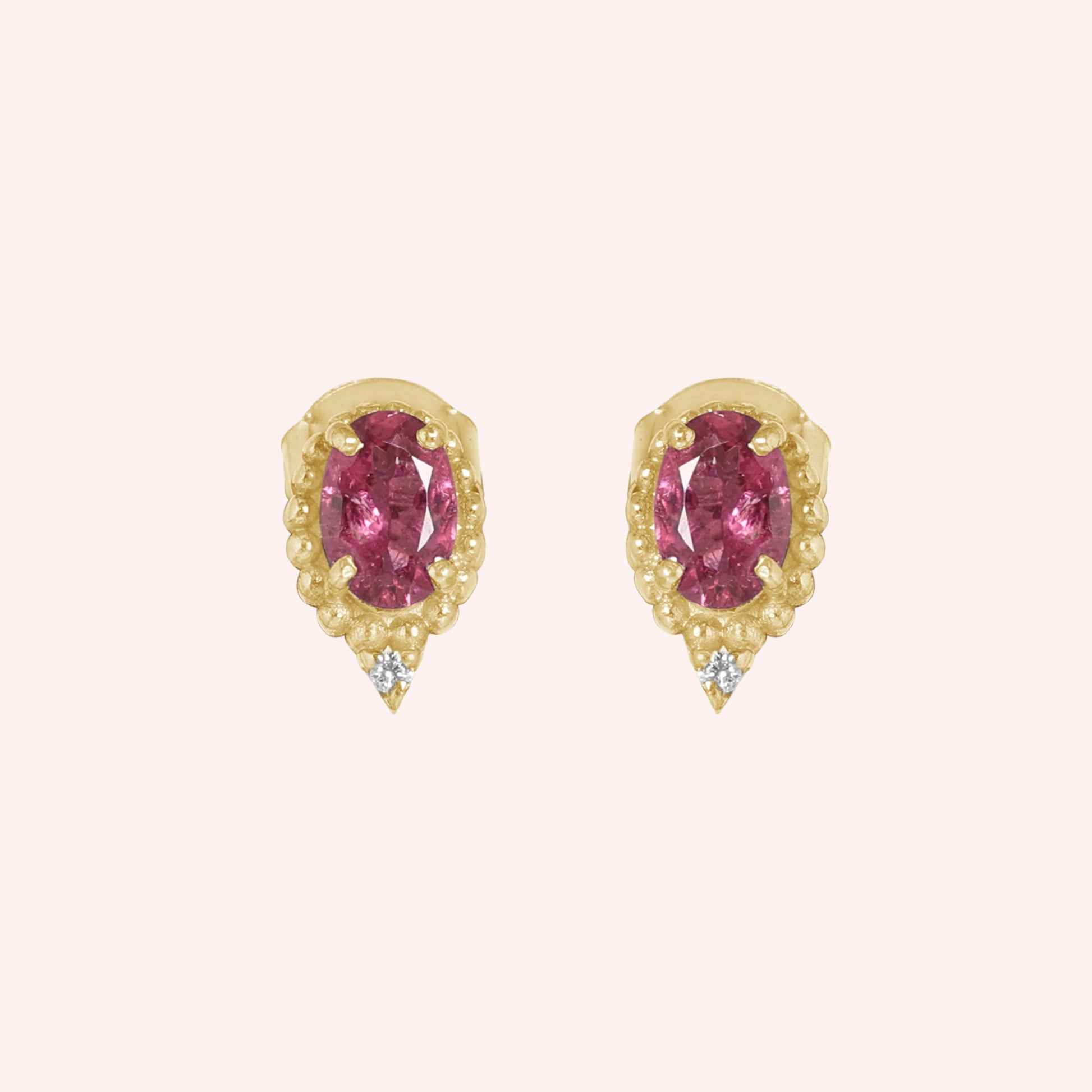 Pink_tourmaline_earrings_in_gold_plated_silver_with_oval_stone_and_a_white_topaz_shown_front_angle_view_on_solid_pink_background
