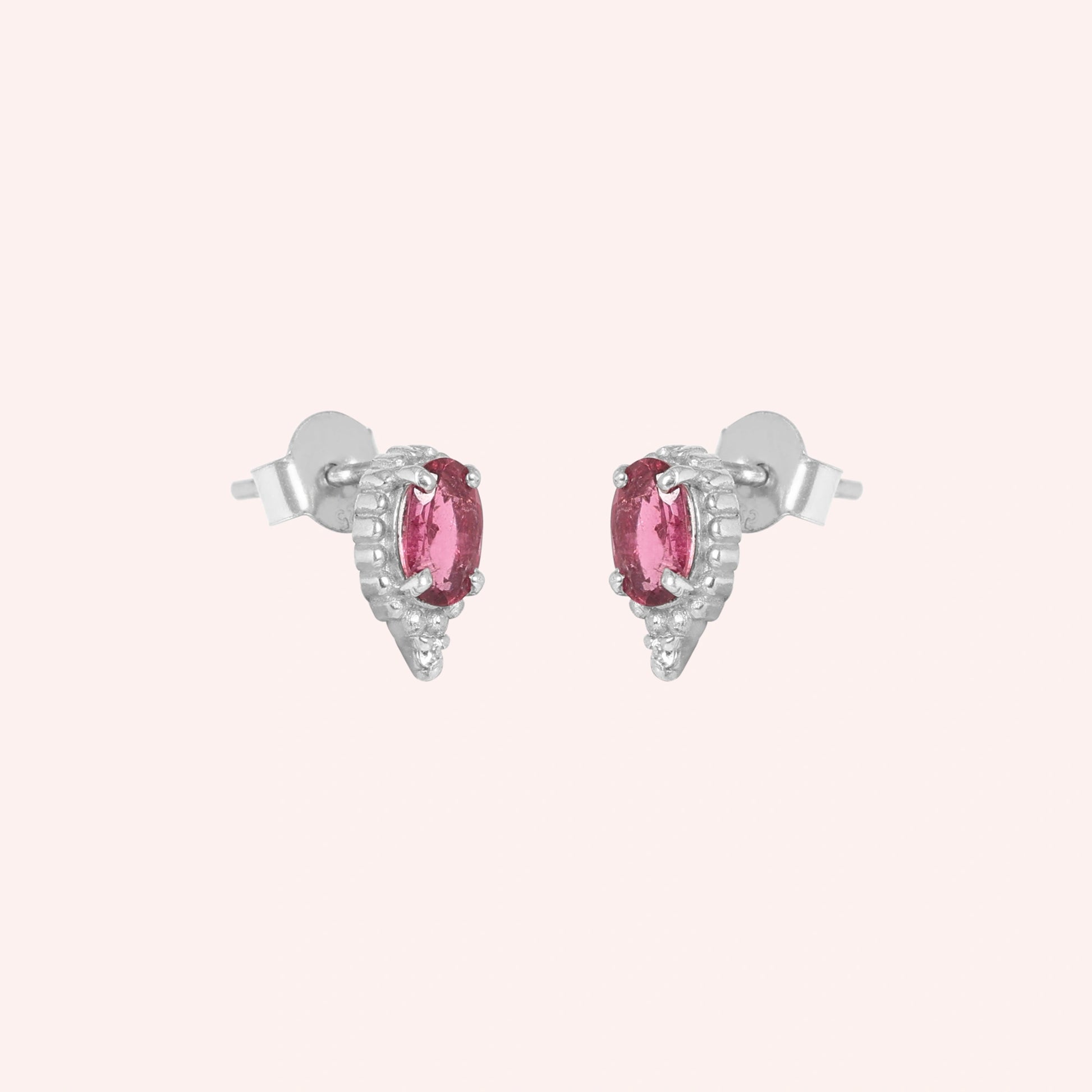 Pink_tourmaline_earrings_in_sterling_silver_with_oval_stone_and_a_white_topaz_in_slightly_angle_view_on_solid_pink_background