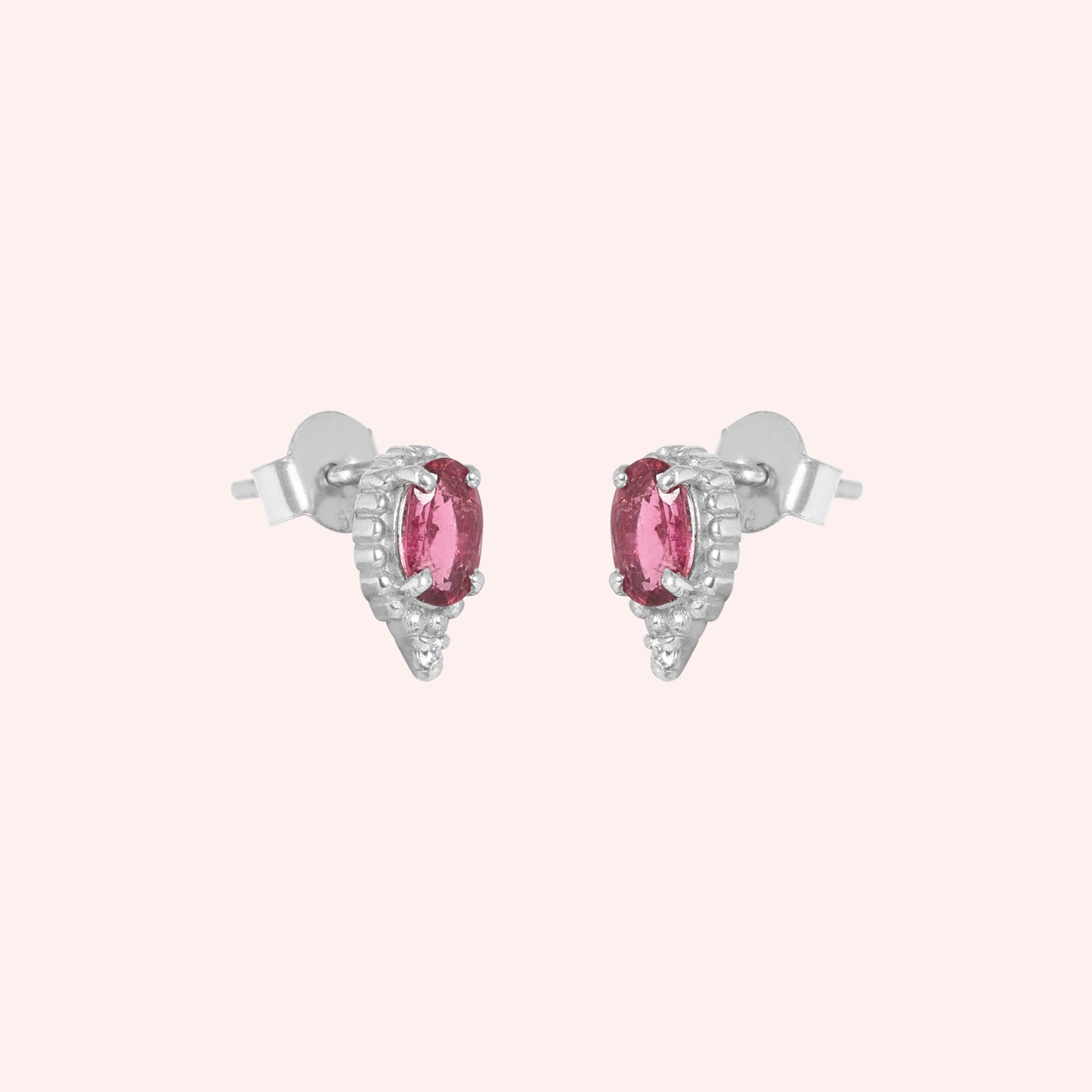 Pink_tourmaline_earrings_in_sterling_silver_with_oval_stone_and_a_white_topaz_in_slightly_angle_view_on_solid_pink_background