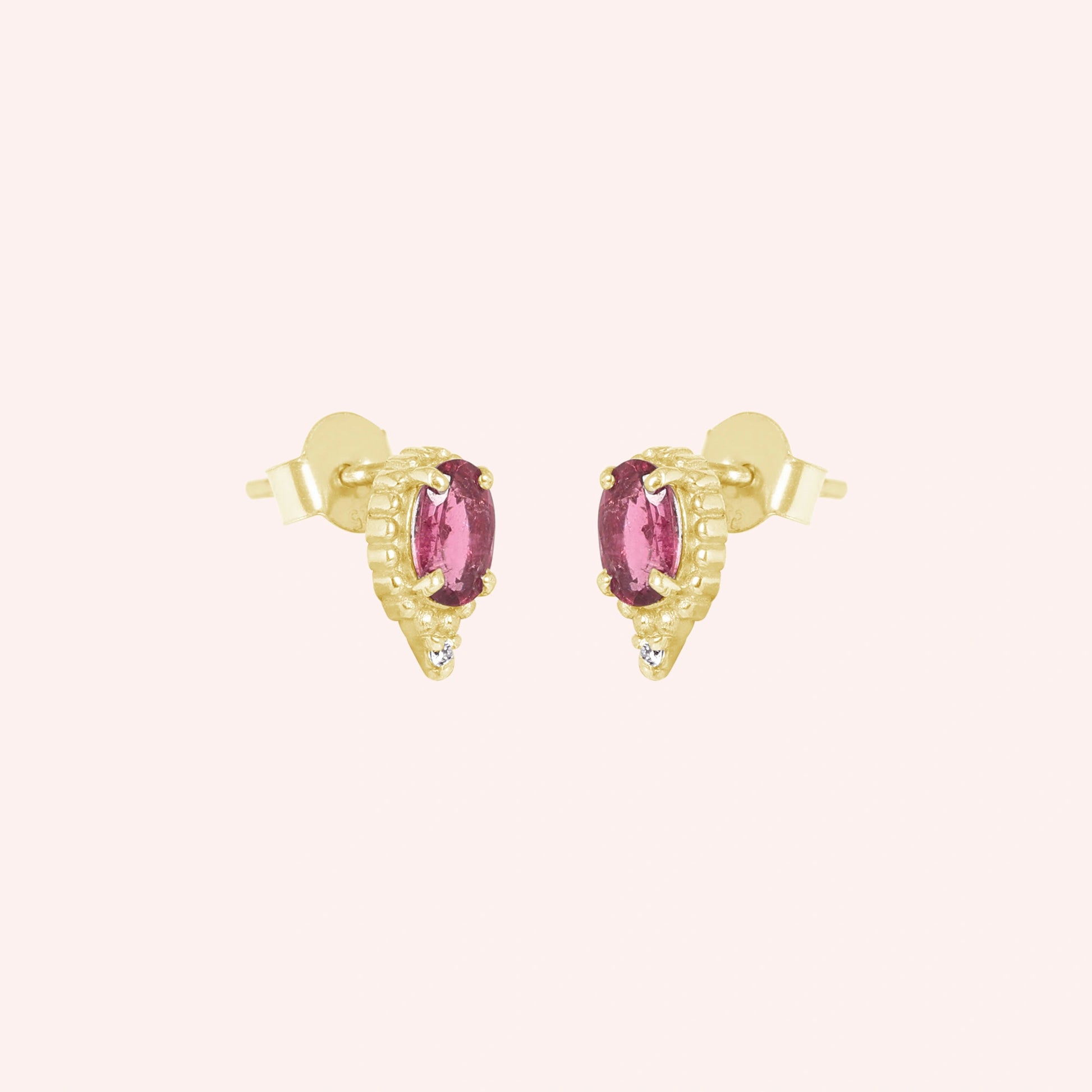 Pink_tourmaline_earrings_in_gold_plated_silver_with_oval_stone_and_a_white_topaz_in_slightly_angle_view_on_solid_pink_background