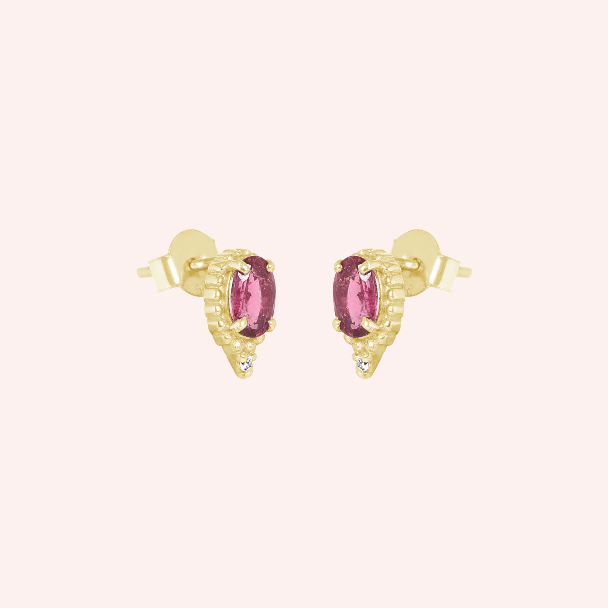 Pink_tourmaline_earrings_in_gold_plated_silver_with_oval_stone_and_a_white_topaz_in_slightly_angle_view_on_solid_pink_background