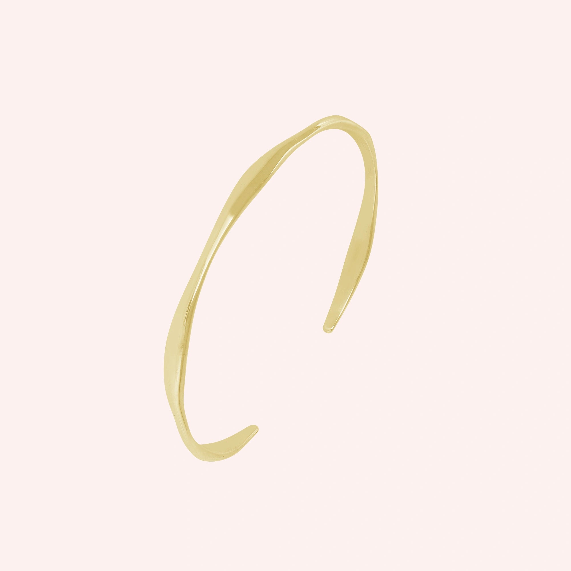 Plain_bangle_in_gold_plated_silver_at_slight_angle_view_on_solid_pink_background