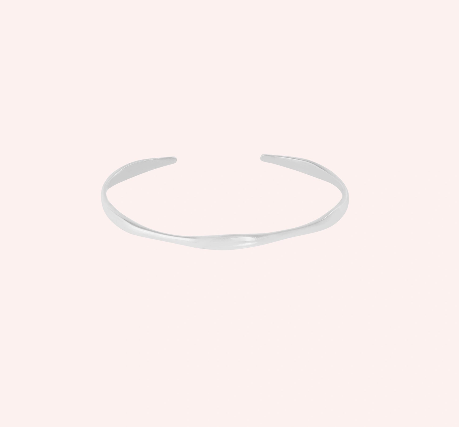 Plain_bangle_in_sterling_silver_at_front_angle_view_on_solid_pink_background