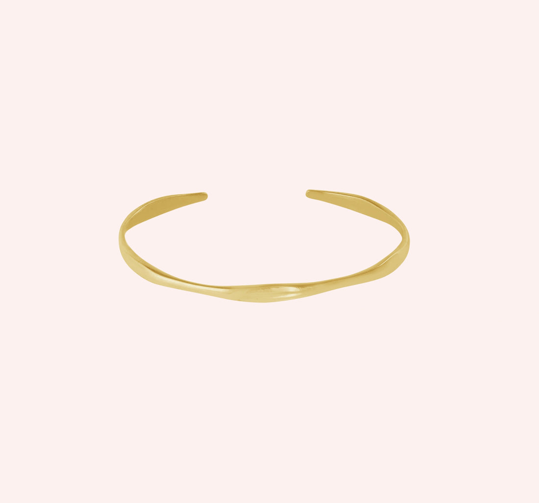 Plain_bangle_in_gold_plated_silver_at_front_angle_view_on_solid_pink_background