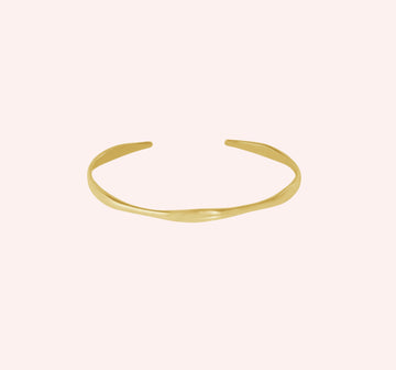 Plain_bangle_in_gold_plated_silver_at_front_angle_view_on_solid_pink_background
