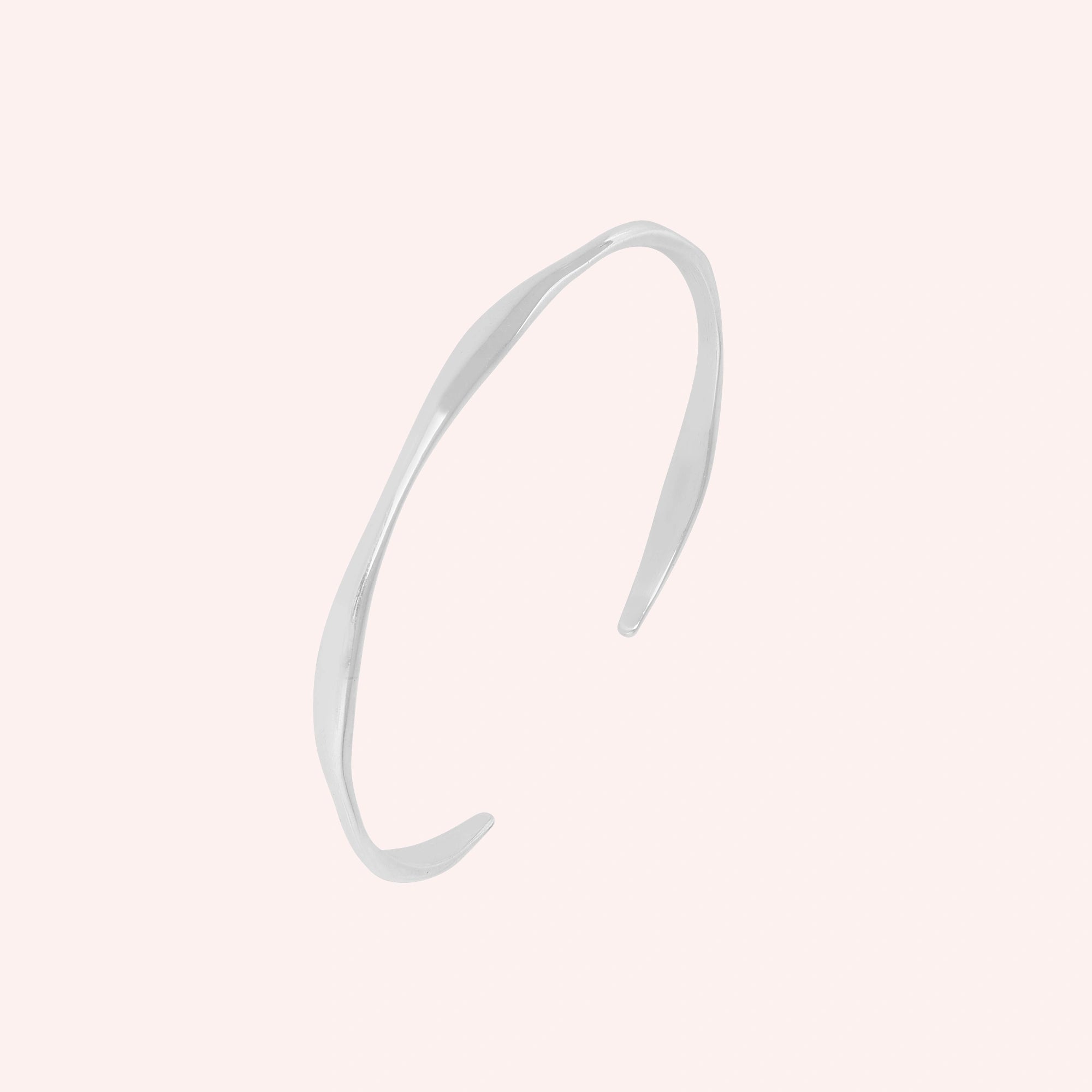 Plain_bangle_in_sterling_silver_at_slight_angle_view_on_solid_pink_background