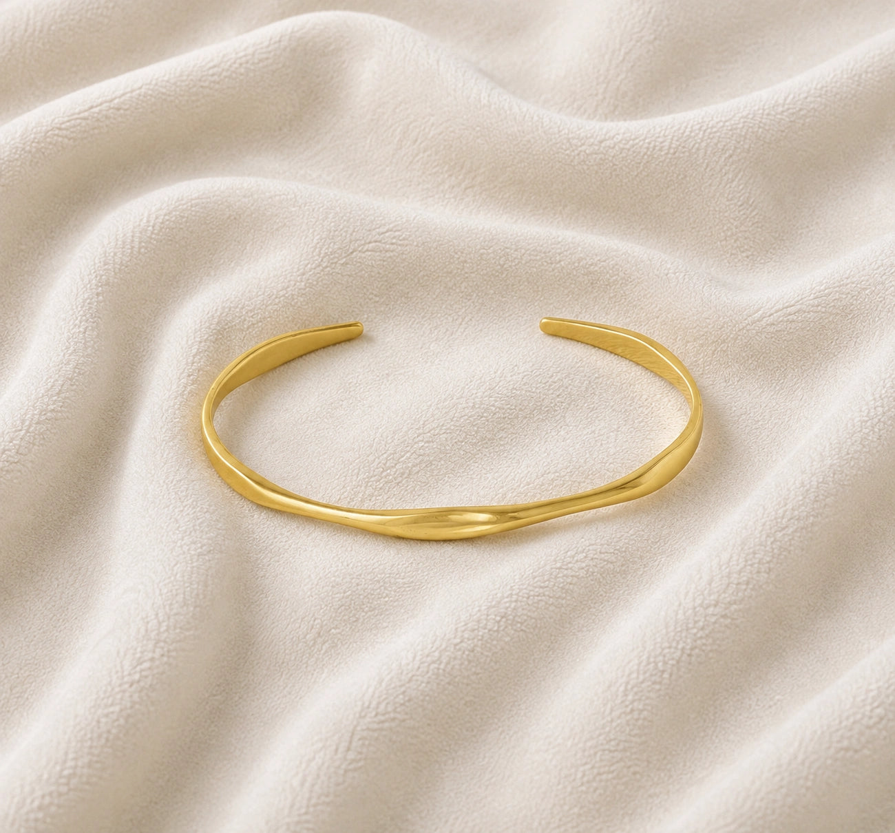 Plain_bangle_in_gold_plated_silver_at_front_angle_view_on_soft_fabric_background