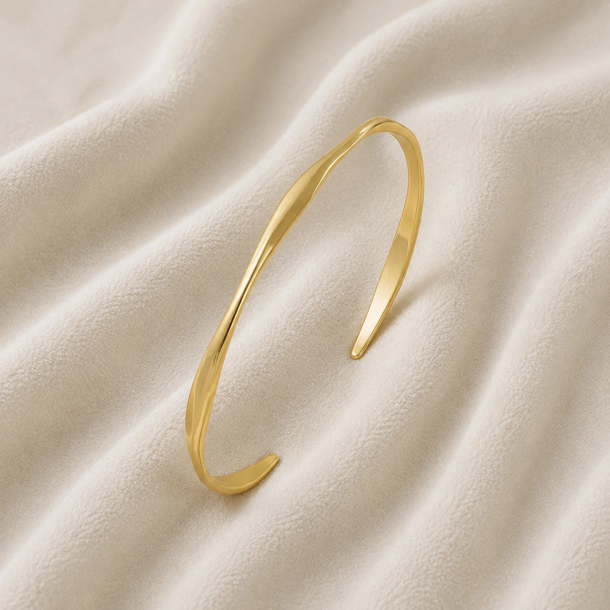 Plain_bangle_in_gold_plated_silver_at_slight_angle_view_on_soft_fabric_background