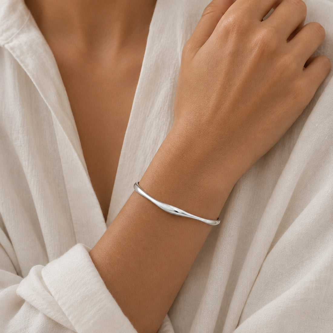 Plain_bangle_in_gold_plated_silver_at_front_angle_view_on_soft_fabric_background