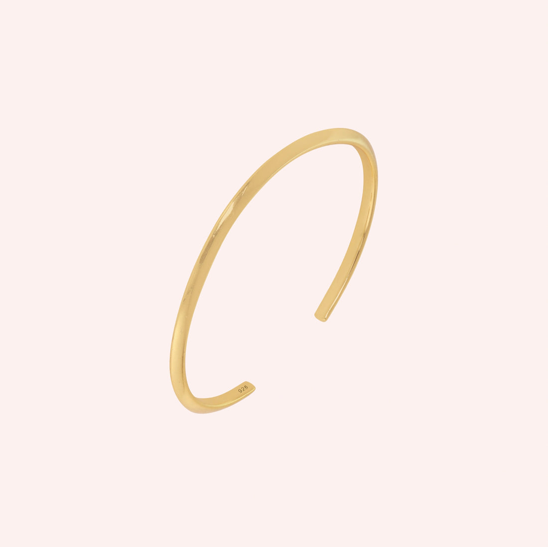 Plain_gold_bangle_in_gold_plated_silver_at_slight_angle_view_on_solid_pink_background