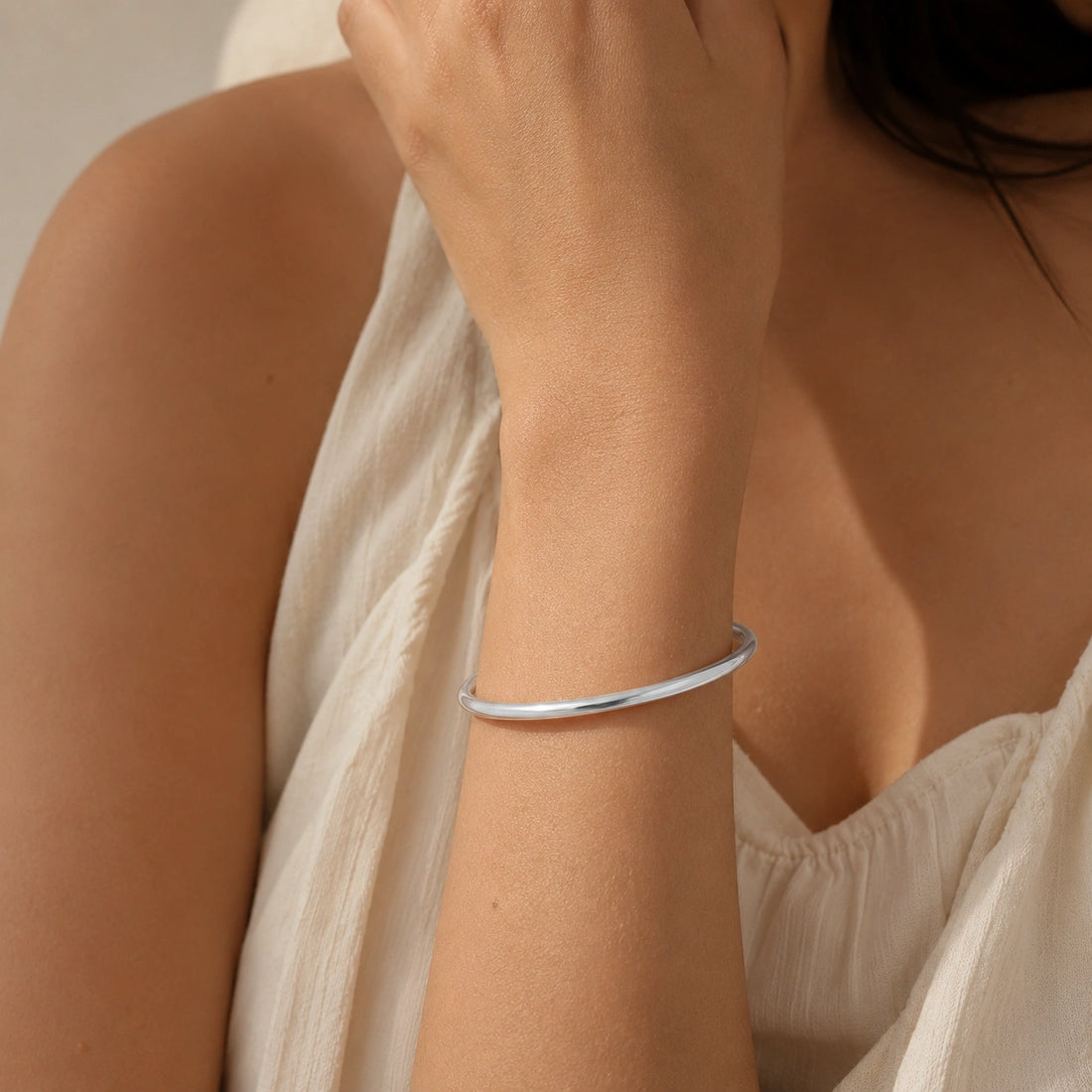 Plain_gold_bangle_in_gold_plated_silver_at_slight_angle_view_on_soft_fabric_background