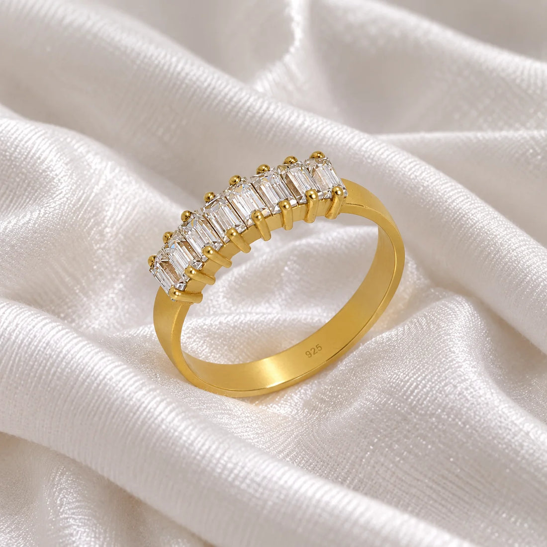 Promise_ring_in_gold_plated_silver_with_baguette_cut_lab_grown_diamonds_at_side_angle_view_on_soft_fabric_background