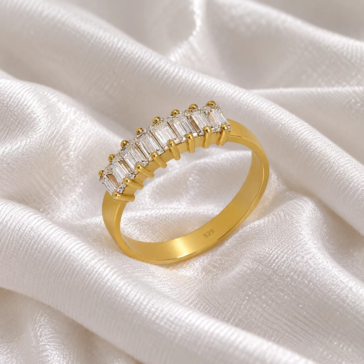 Promise_ring_in_gold_plated_silver_with_baguette_cut_lab_grown_diamonds_at_side_angle_view_on_soft_fabric_background