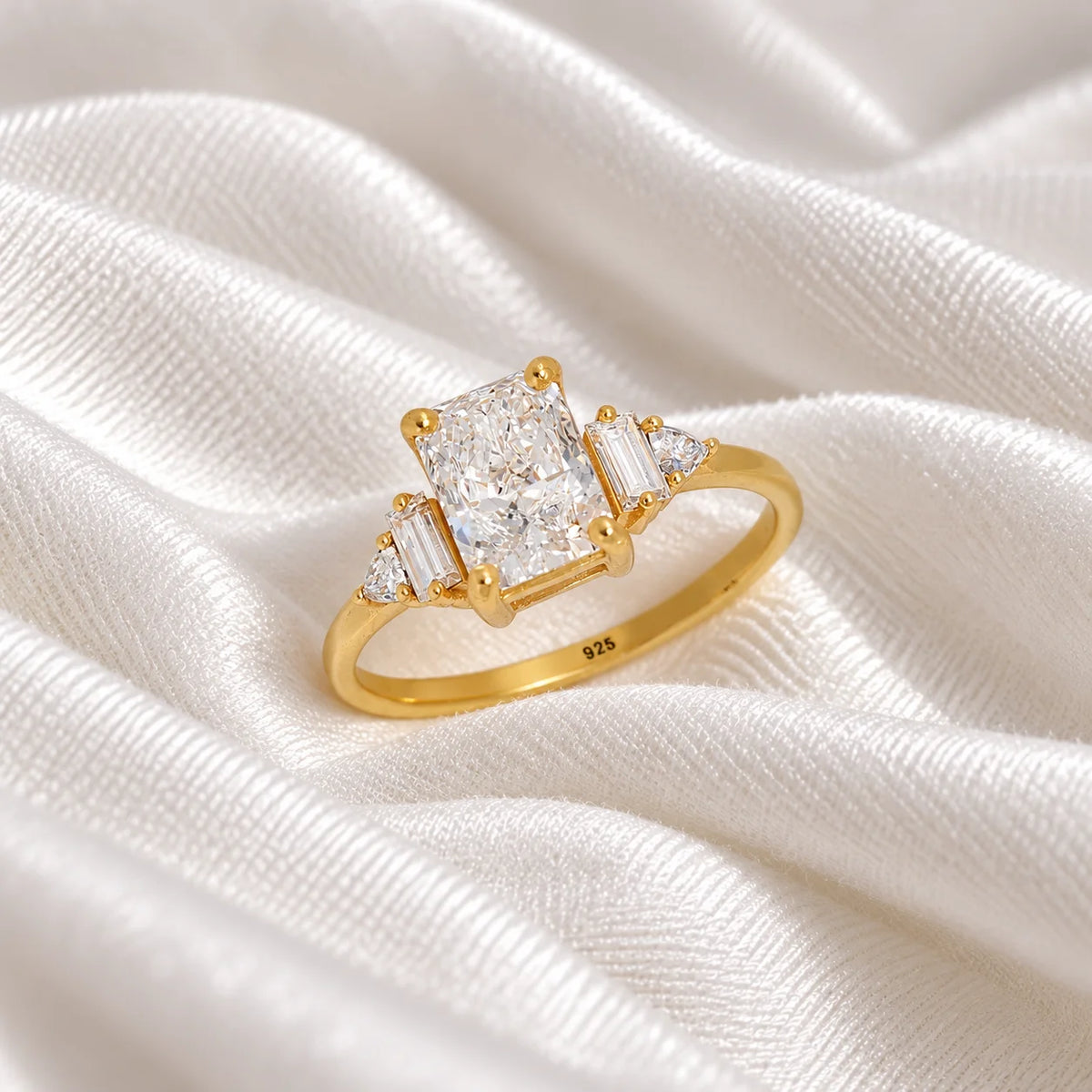 Promise_ring_in_gold_plated_silver_with_five_CZ_stones_at_side_view_on_soft_fabric_background