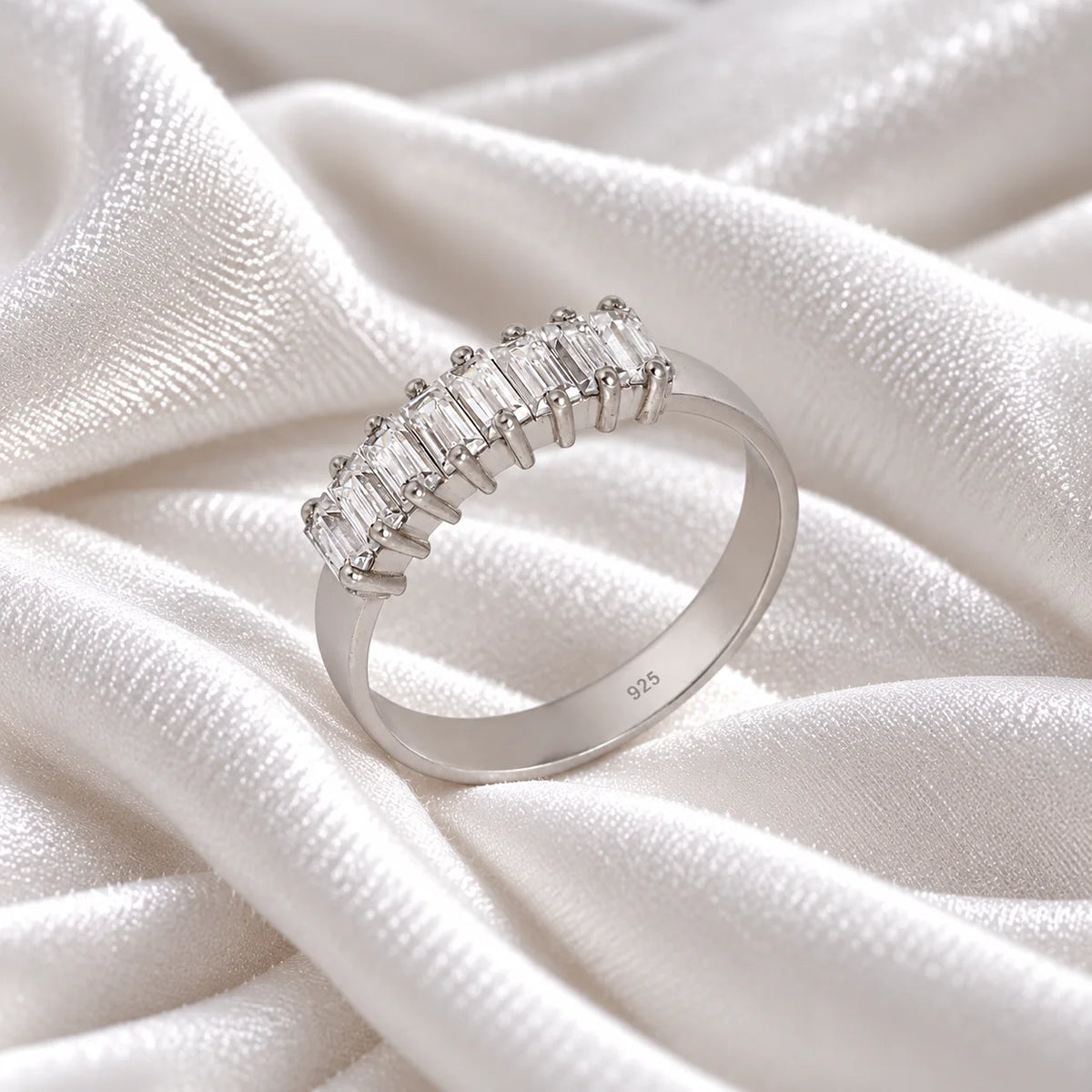 Promise_ring_in_sterling_silver_with_baguette_cut_lab_grown_diamonds_at_side_angle_view_on_soft_fabric_background