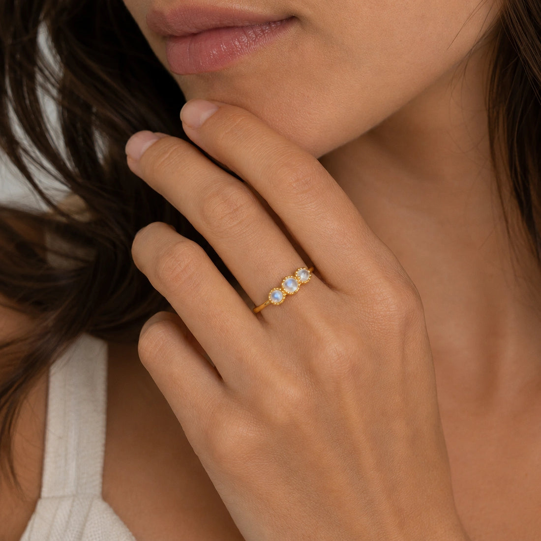 Rainbow_moonstone_ring_in_gold_plated_silver_with_three_moonstones_at_front_angle_on_soft_fabric_background