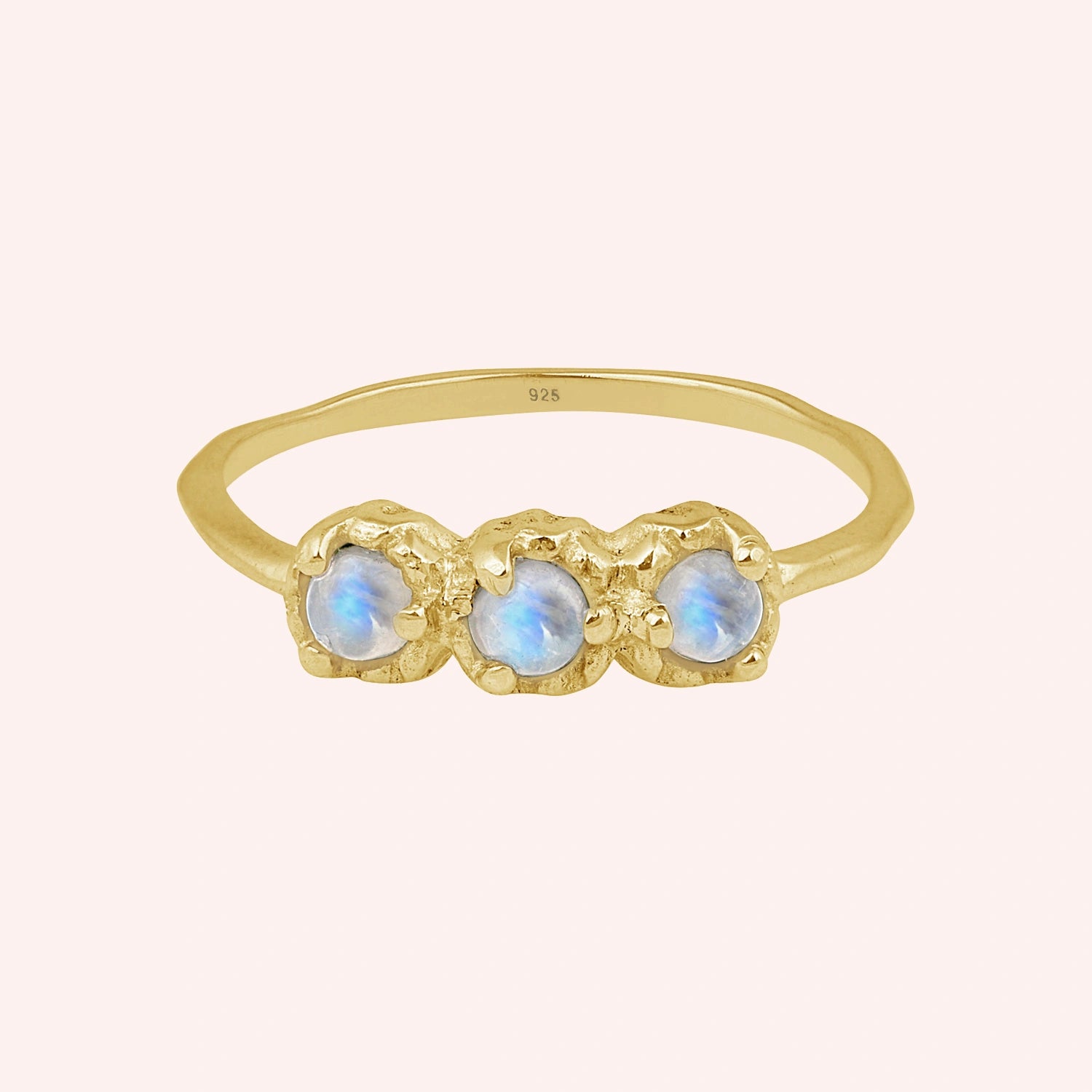 Rainbow_moonstone_ring_in_gold_plated_silver_with_three_moonstones_at_front_angle_on_solid_pink_background