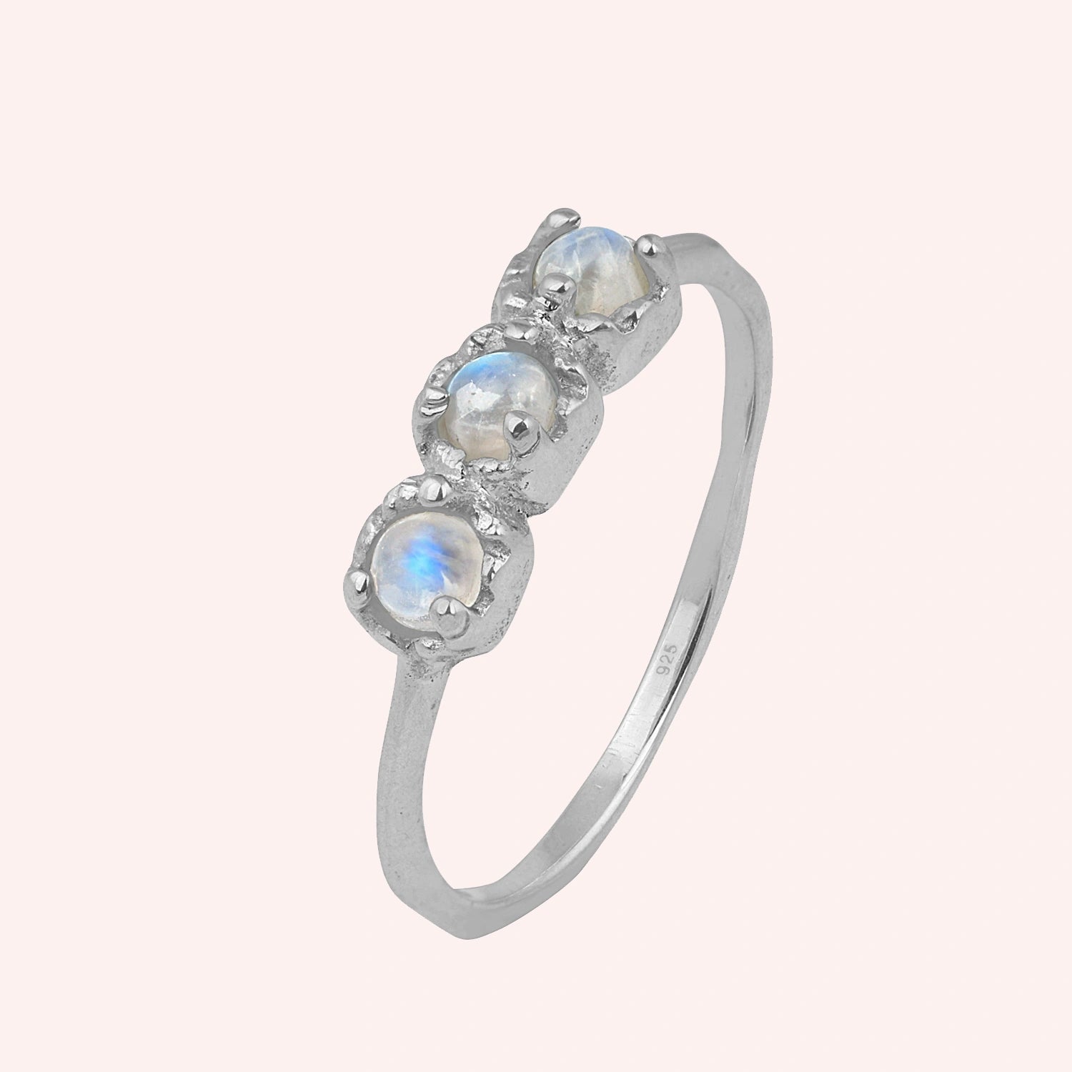 Rainbow_moonstone_ring_in_sterling_silver_with_three_moonstones_at_slight_angle_on_solid_pink_background