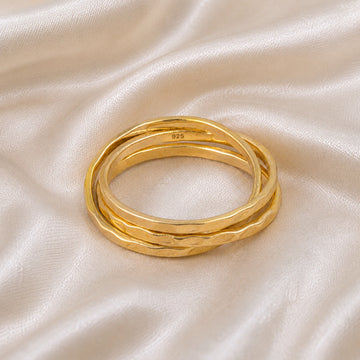 Ring_set_of_three_gold_plated_silver_textured_stacking_bands_at_front_angle_on_soft_fabric_background