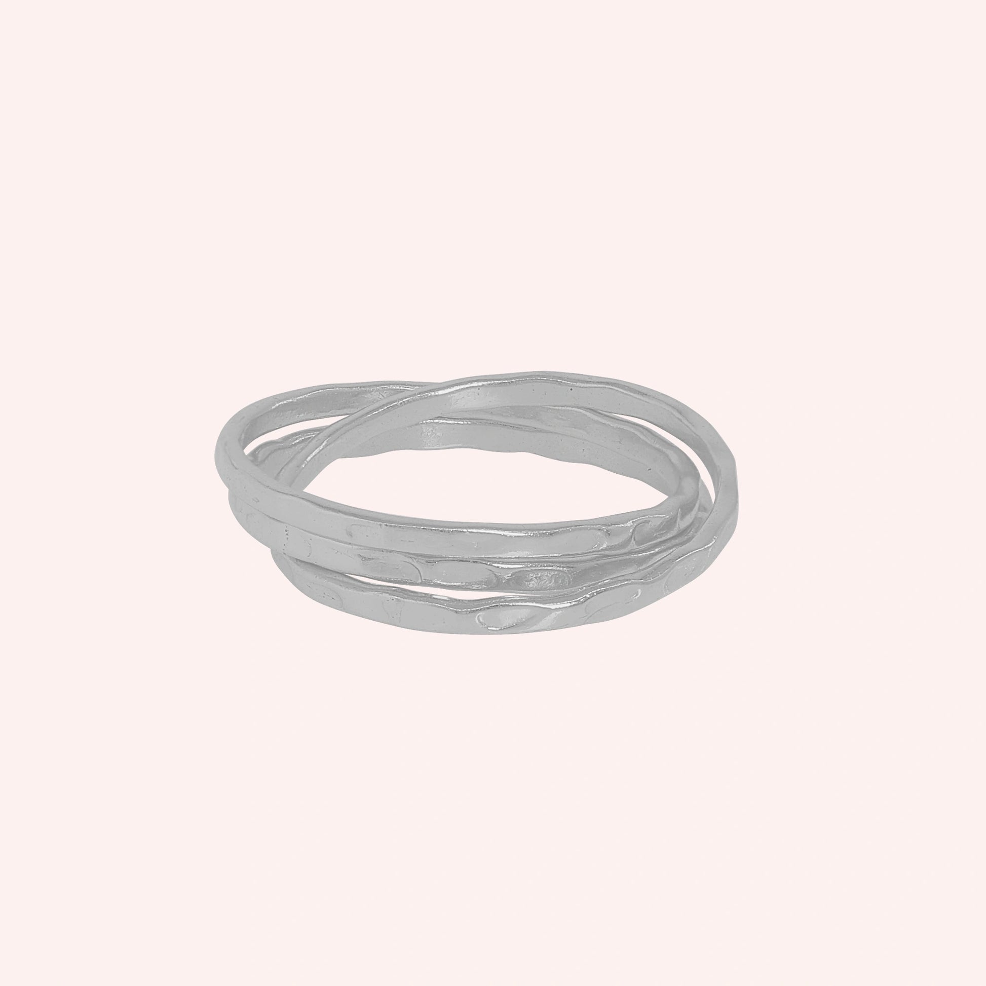 Ring_set_of_three_sterling_silver_textured_stacking_bands_at_front_angle_on_solid_pink_background